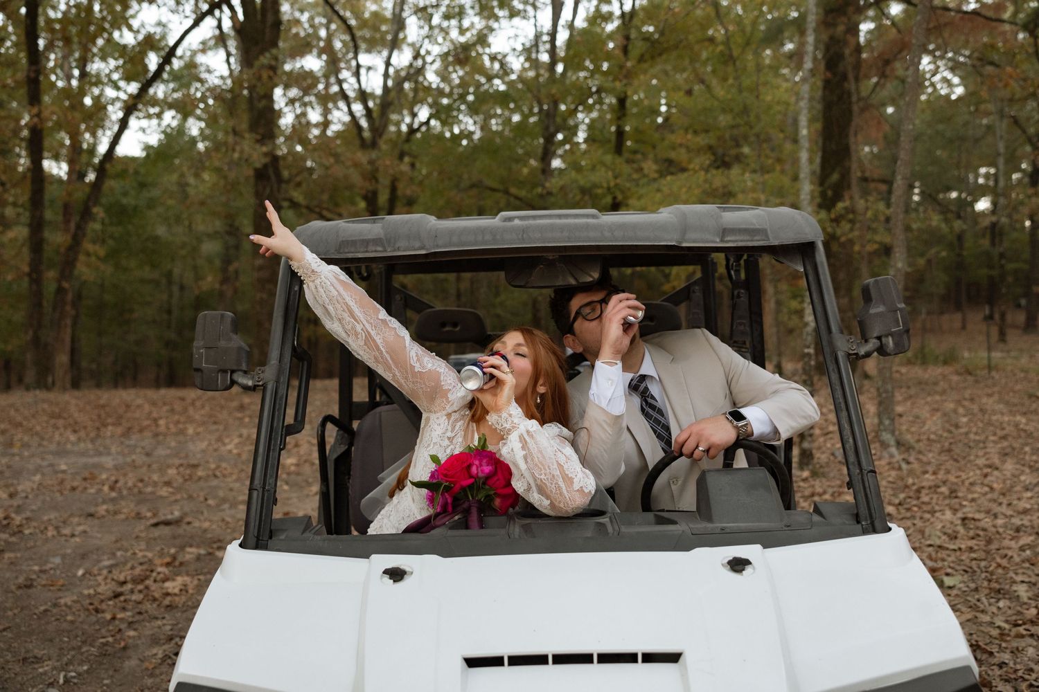 Happy couple poses enthusiastically in a white utility vehicle during their wedding celebration.