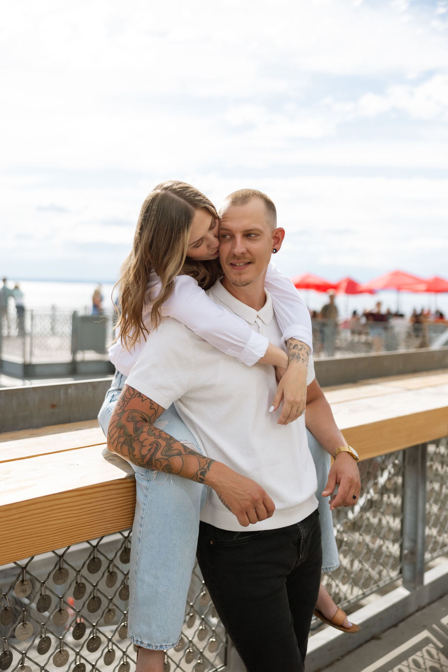 A couple shares an affectionate moment on a deck overlooking Seattle.