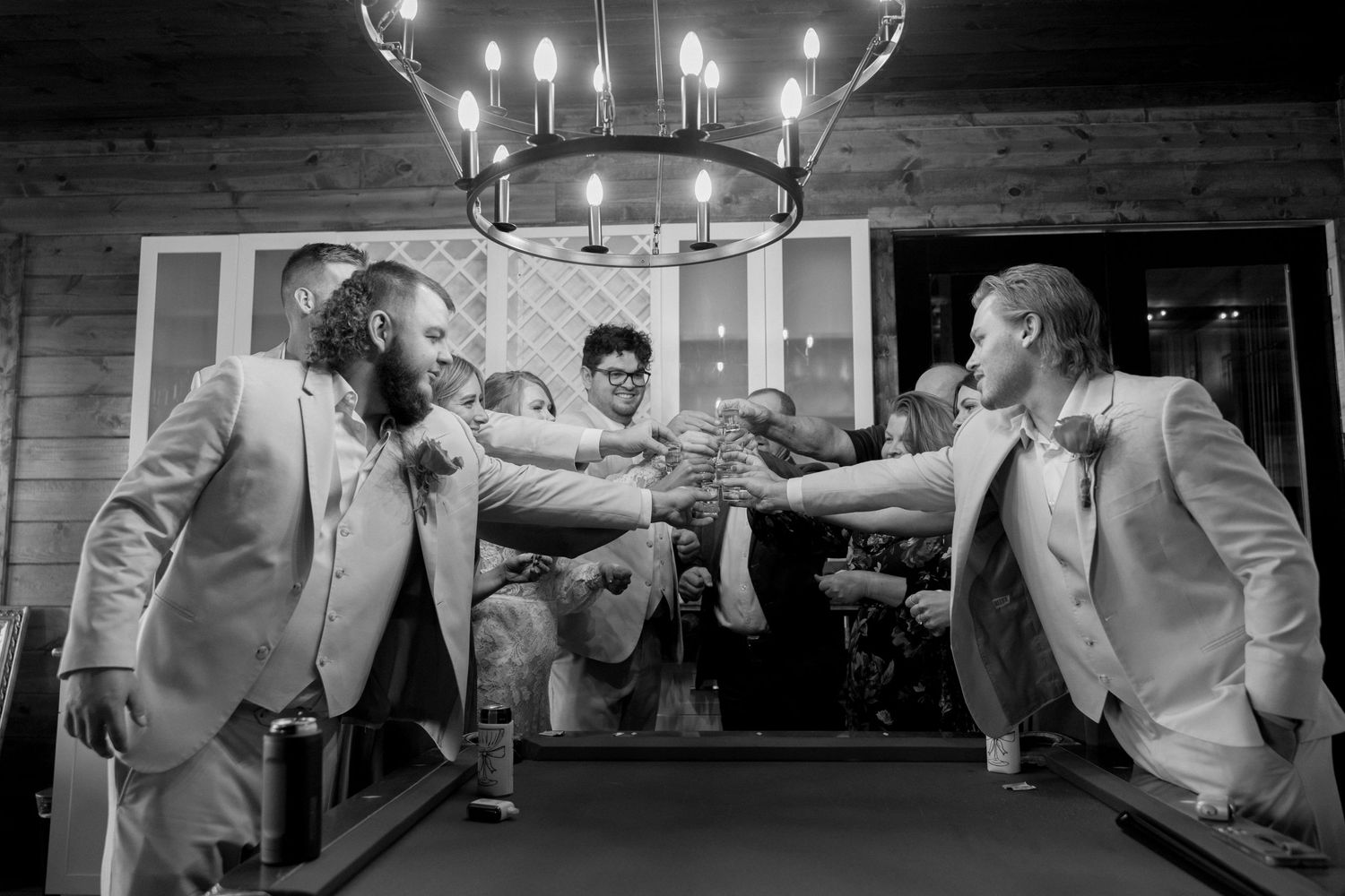 Groomsmen sharing drinks and toasting during wedding celebrations.