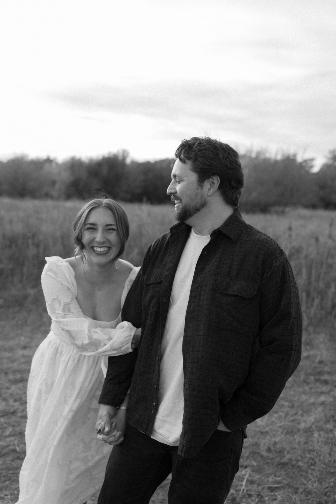Couple shares joyful moment together in rustic field during autumn engagement session.