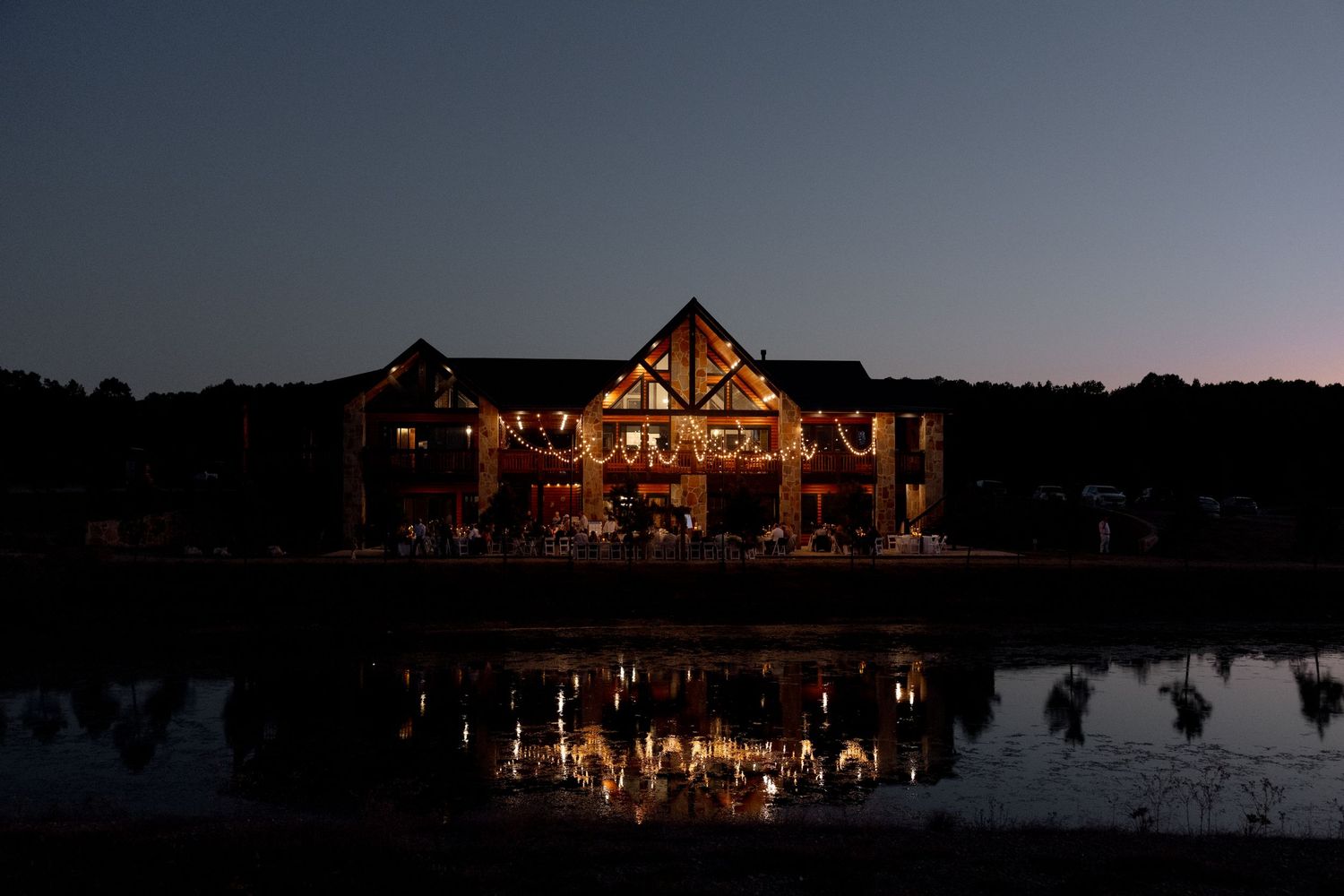 Illuminated lodge venue at night with lights reflecting dramatically in the lake.