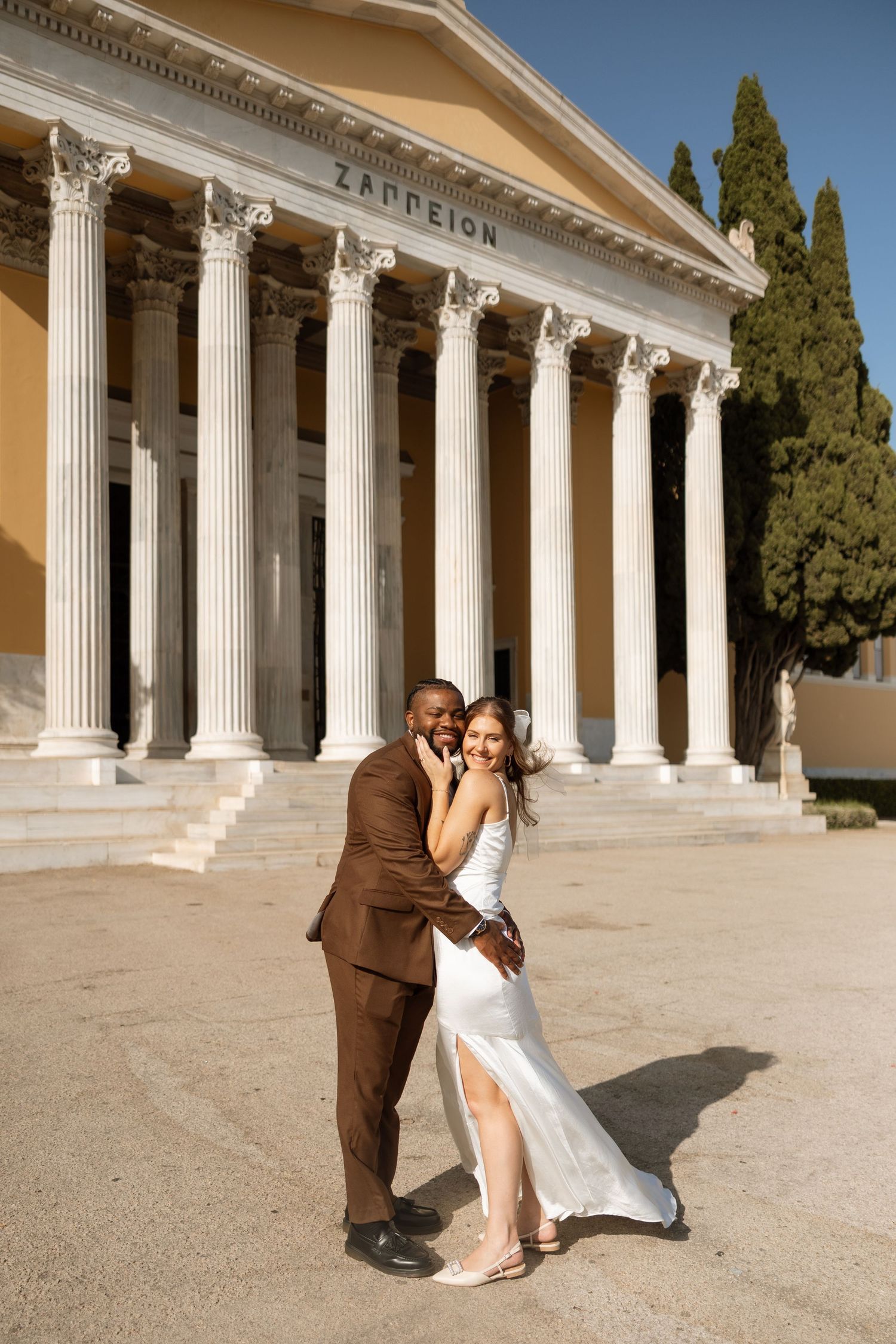 Elegant couple poses for romantic photo in front of historic Zappeion Hall.