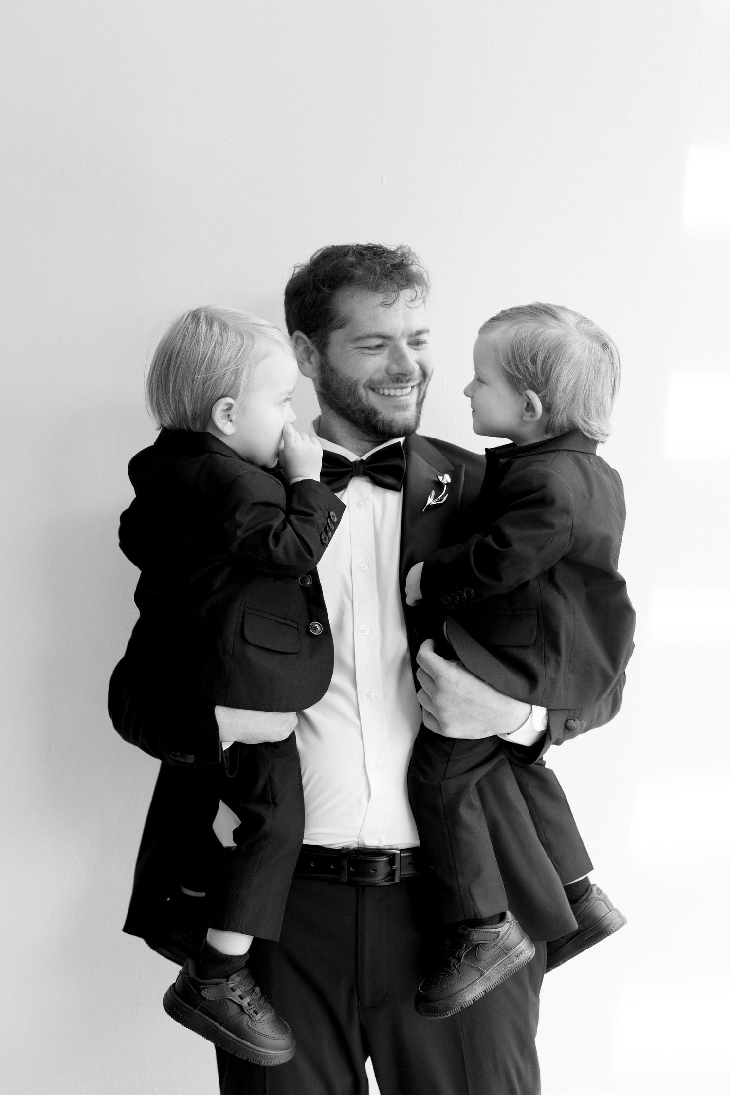 A joyful moment captured in black and white of three people in formal attire sharing laughter together.