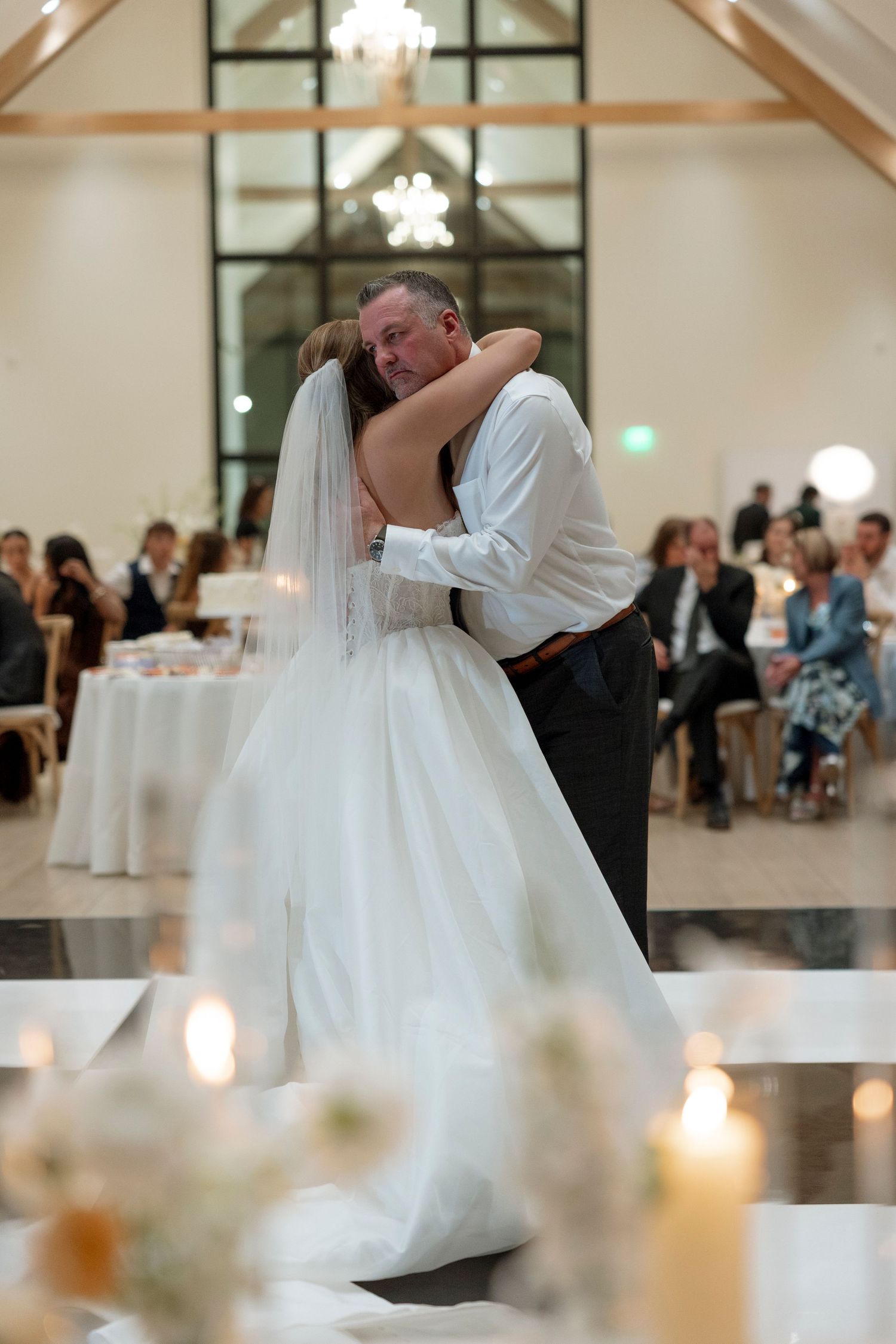 Romantic first dance moment at a wedding reception with candlelit tables in an elegant venue.