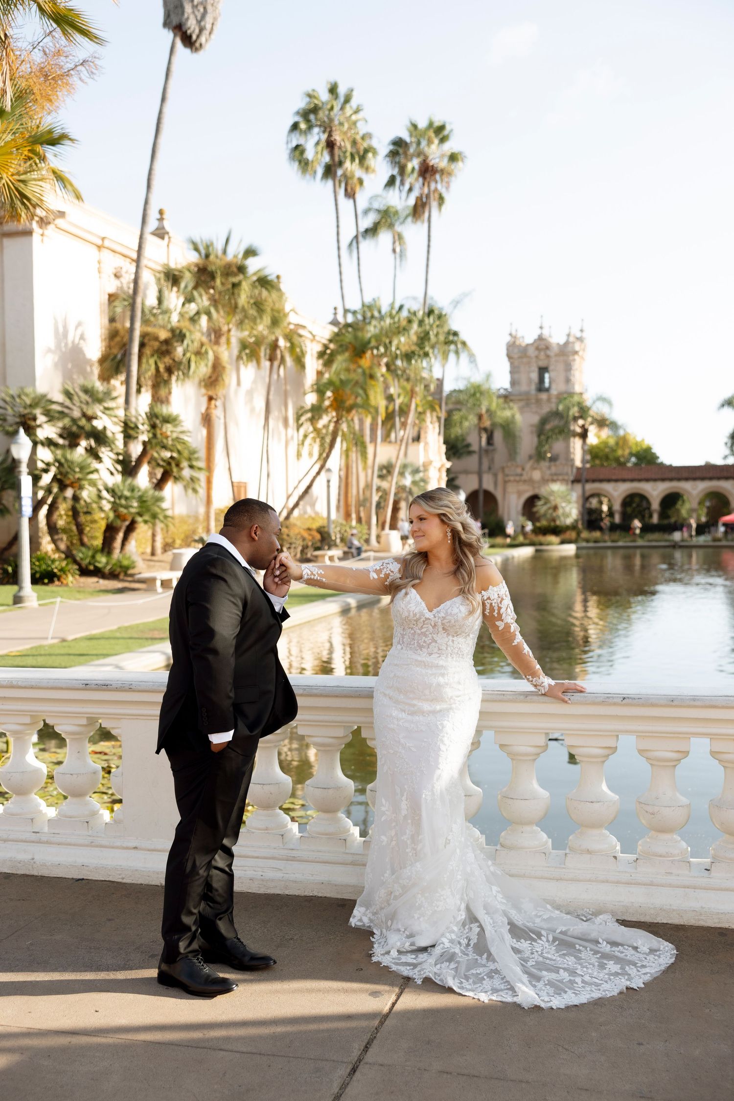 A romantic wedding photoshoot at a Mediterranean-style venue with palm trees and decorative balustrades.
