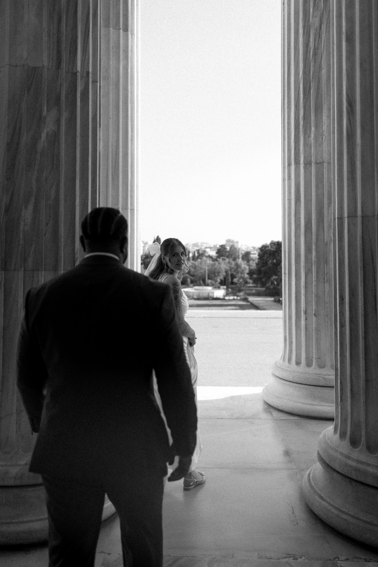 Black and white photo of couple framed between classical columns.