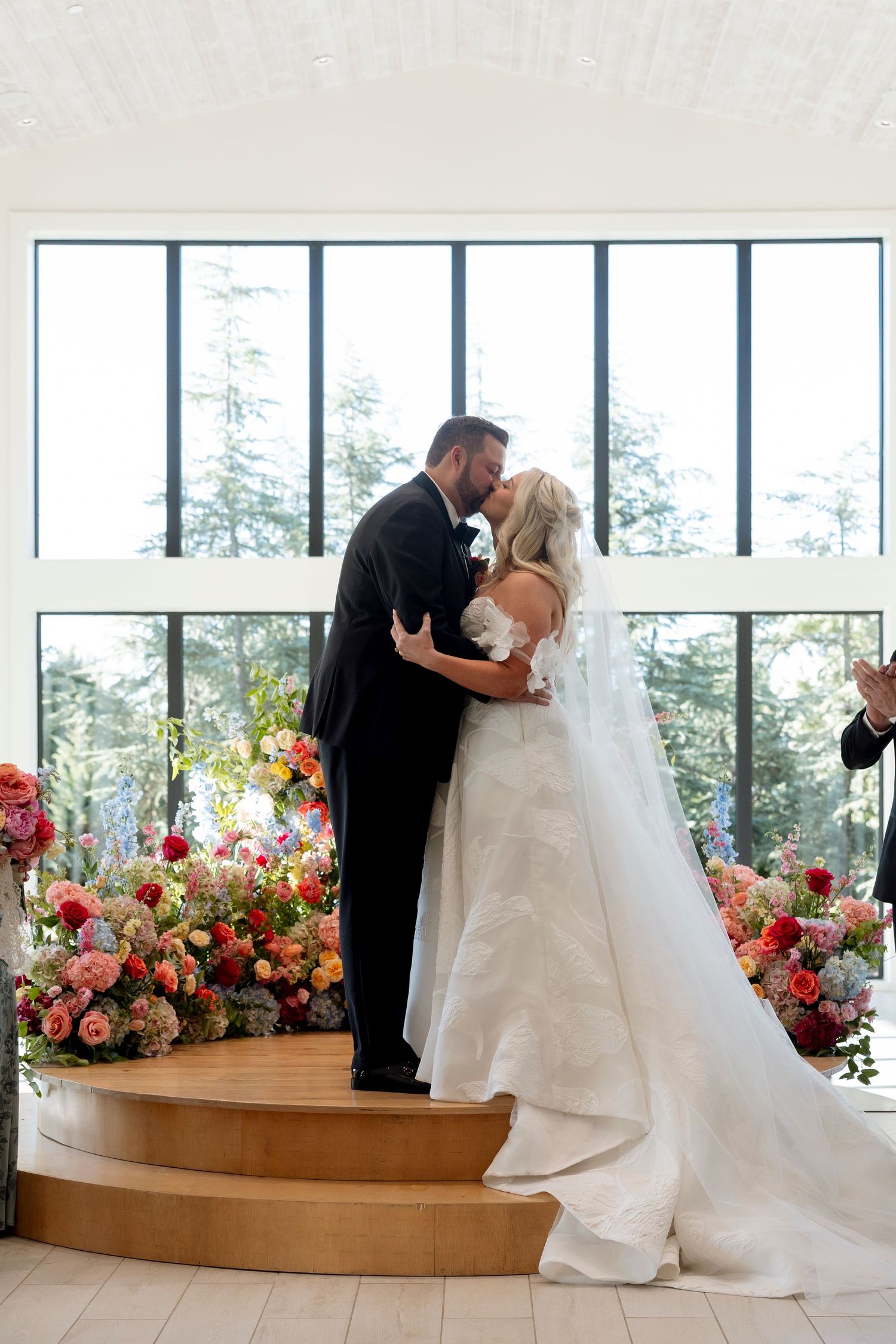 Wedding ceremony space with dramatic floral arrangements and large windows.
