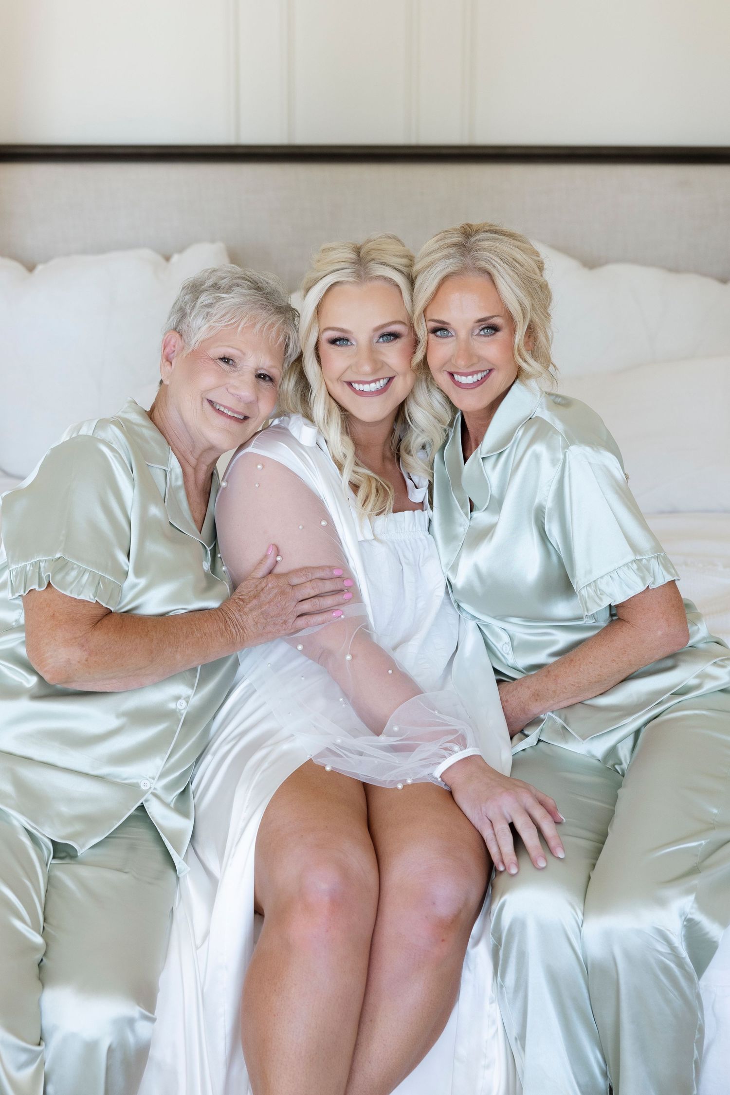 Wedding morning preparations with attendants in matching silk robes lounging on white furniture.