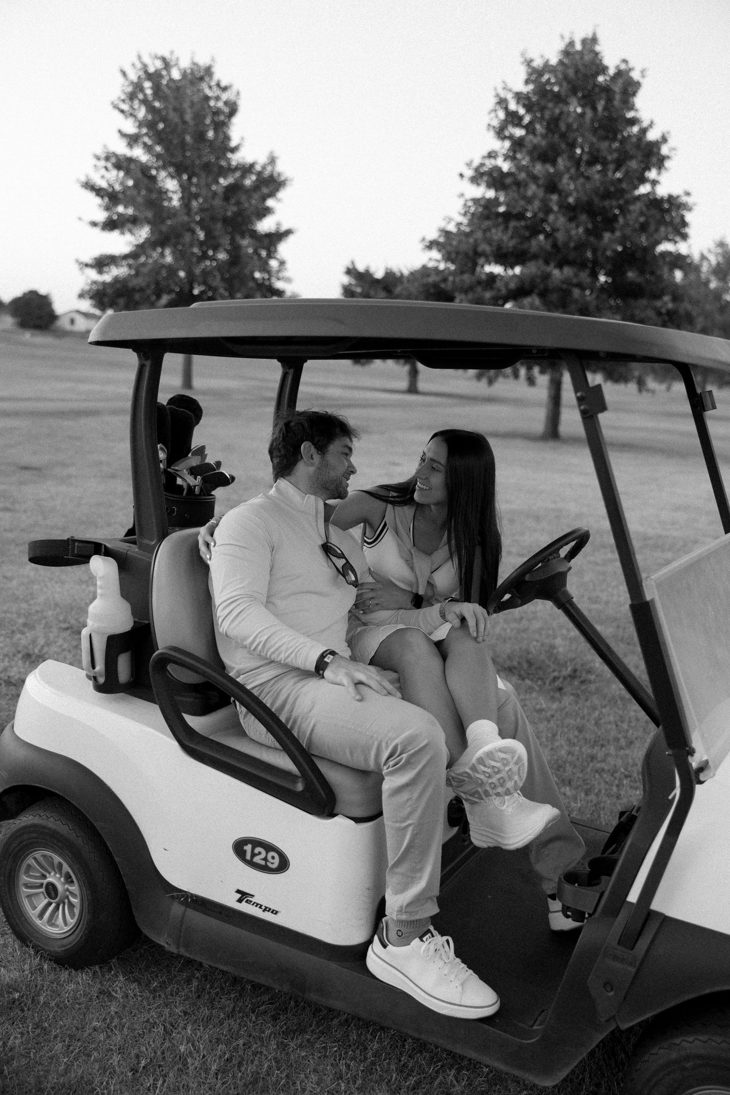 A romantic couple sharing an intimate moment in a golf cart on a course.