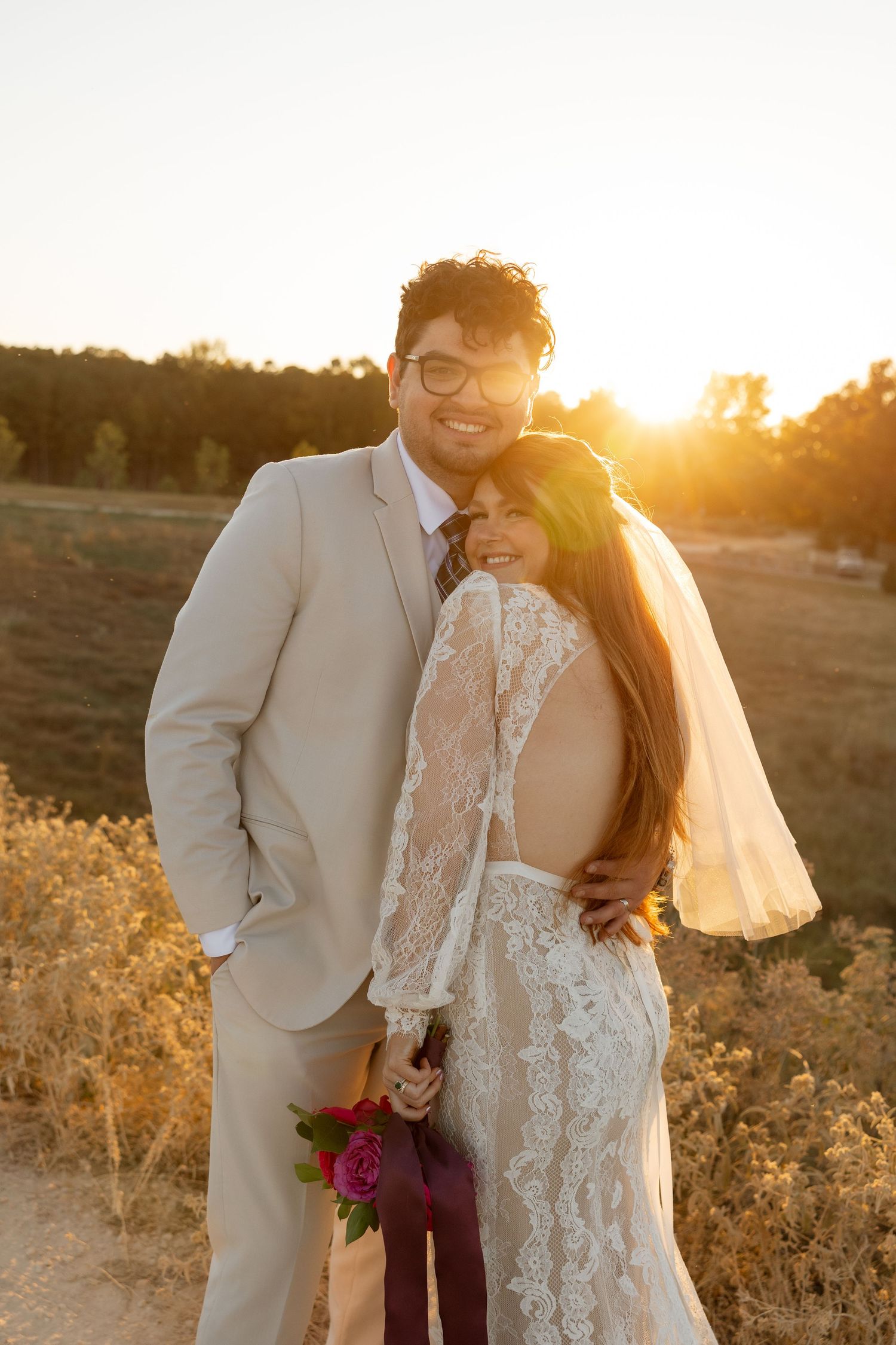 A warm sunset portrait of newlyweds sharing an intimate moment in their wedding attire.
