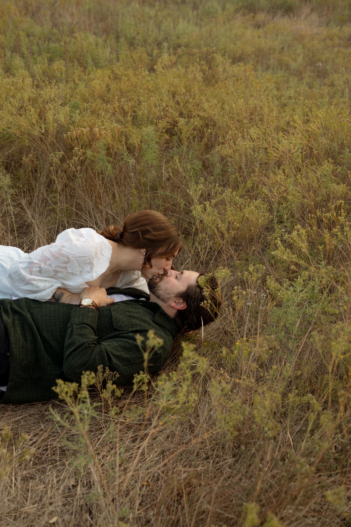 A romantic moment captured in a golden autumn field with tall grass surrounding the couple.