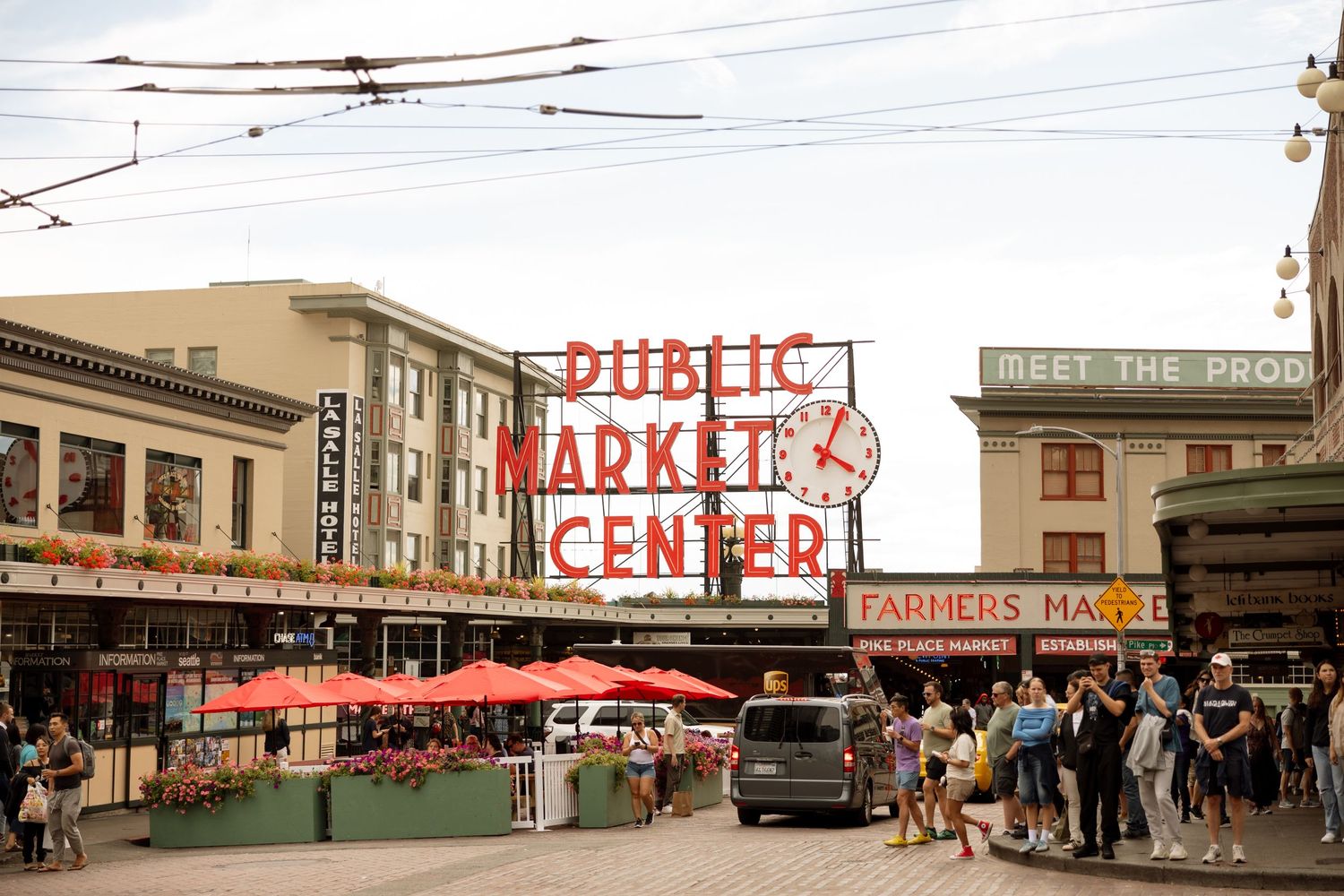 Historic Pike Place Market entrance with red neon sign and crowds below.