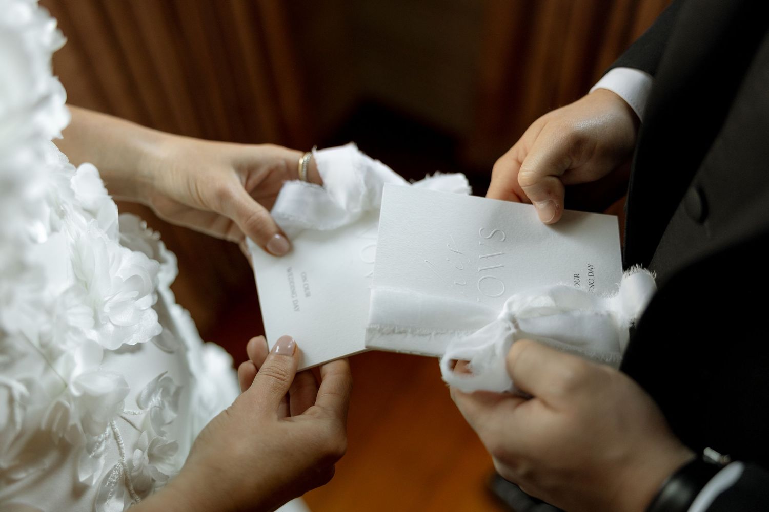Bride and groom exchange handwritten vow letters during intimate wedding ceremony moment.