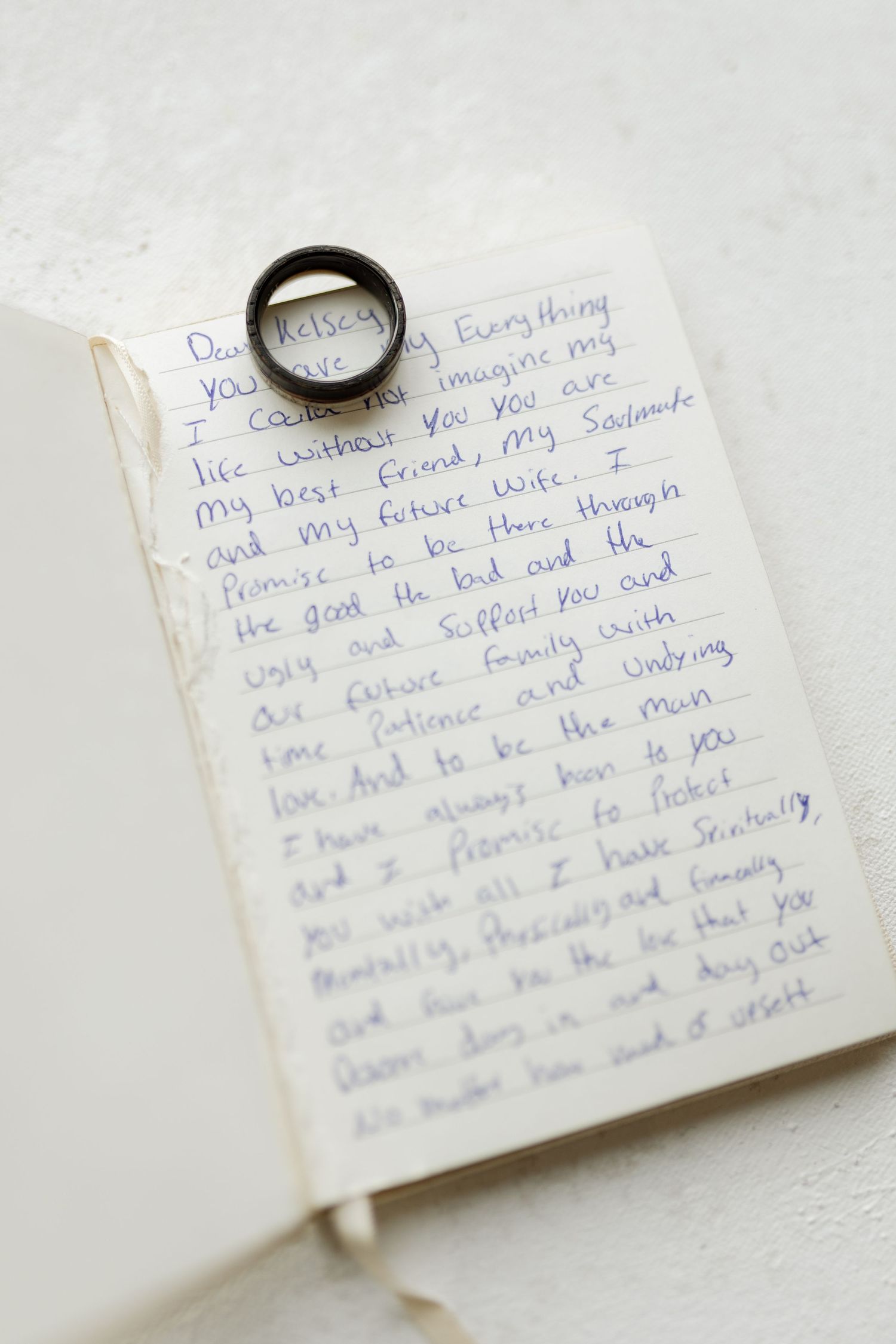 Wedding ring placed on handwritten vows in a journal.