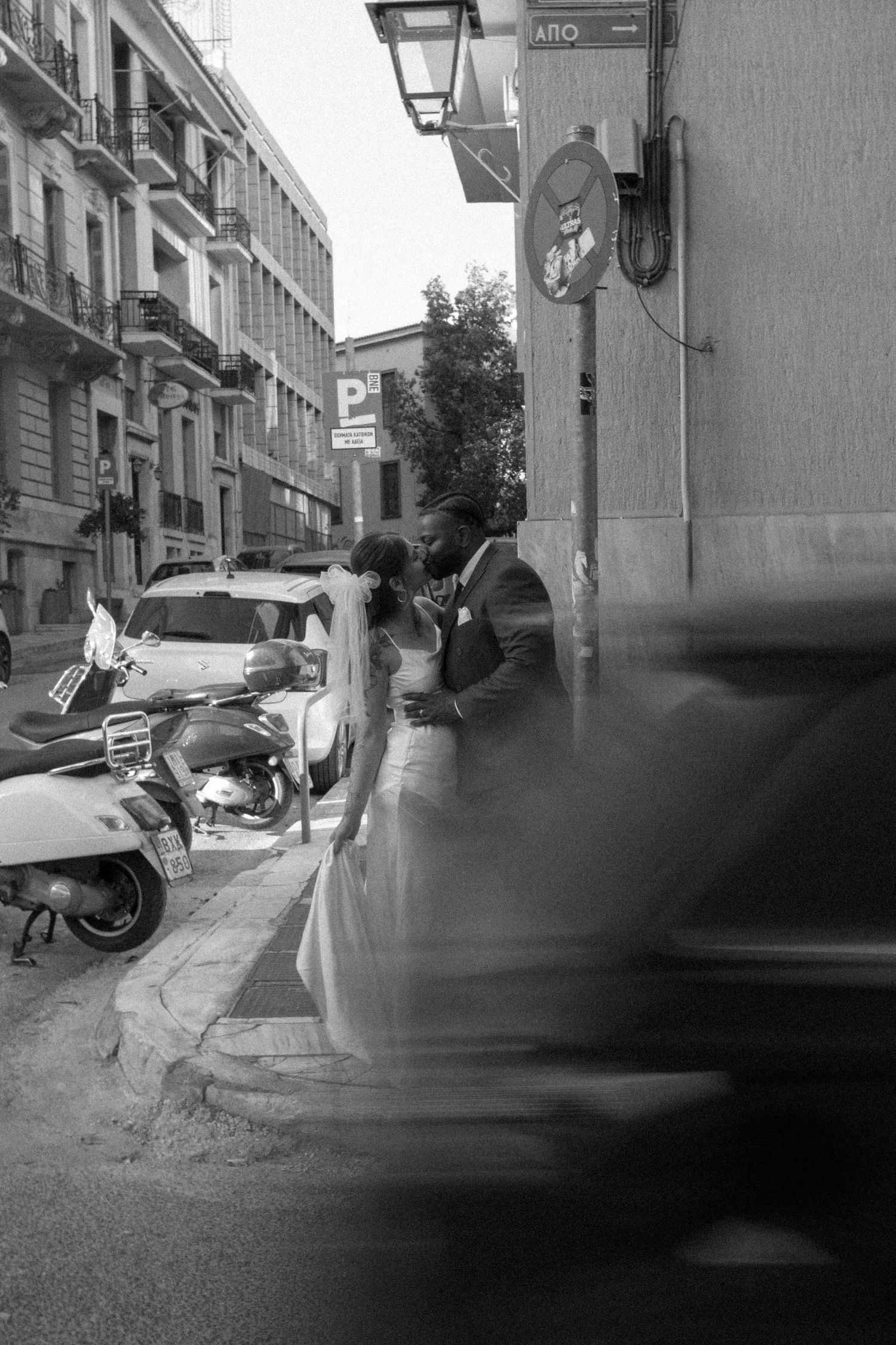 Artistic black and white photo capturing motion blur on a European street with parked scooters.