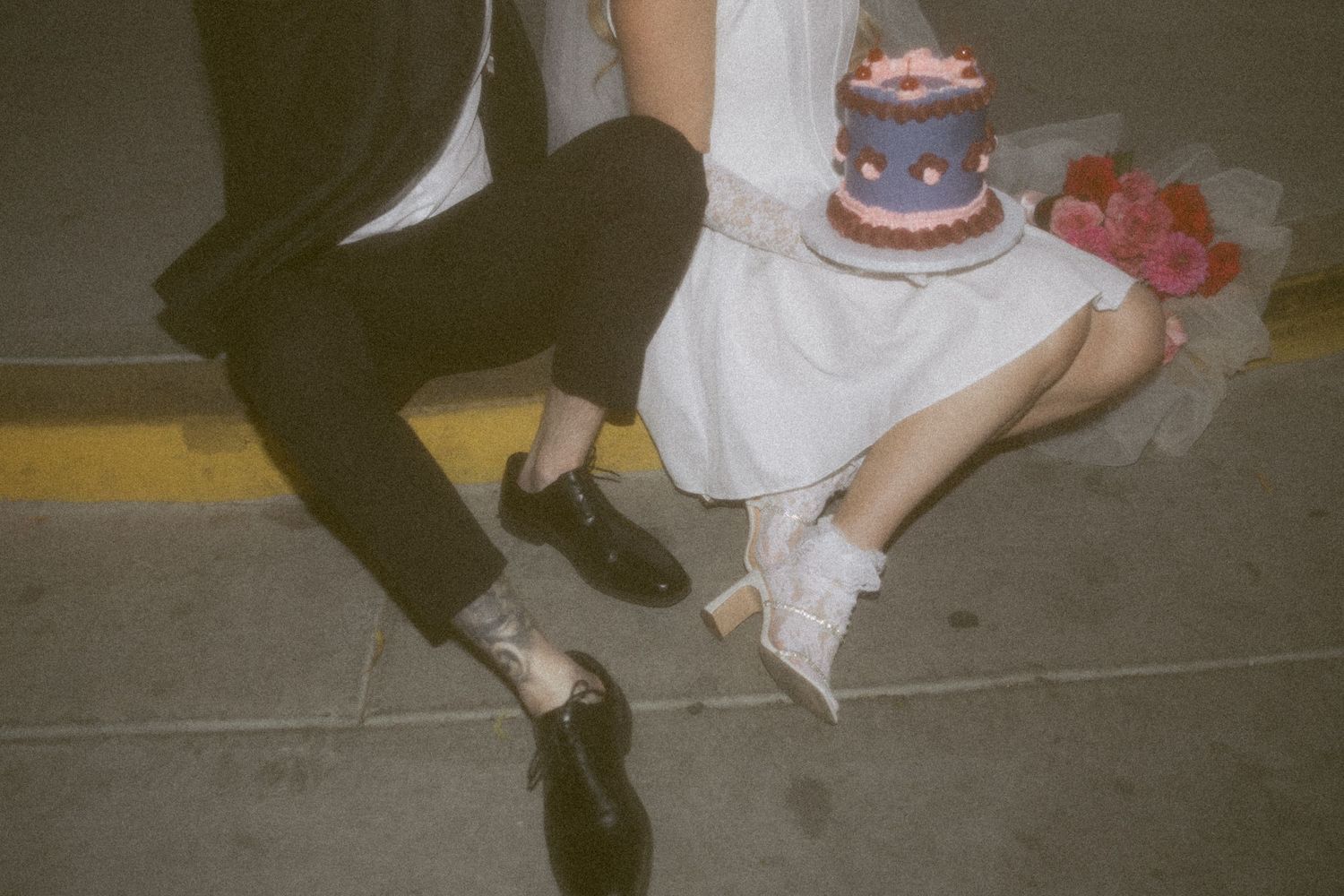 A casual wedding moment showing dress shoes and cake on the ground.