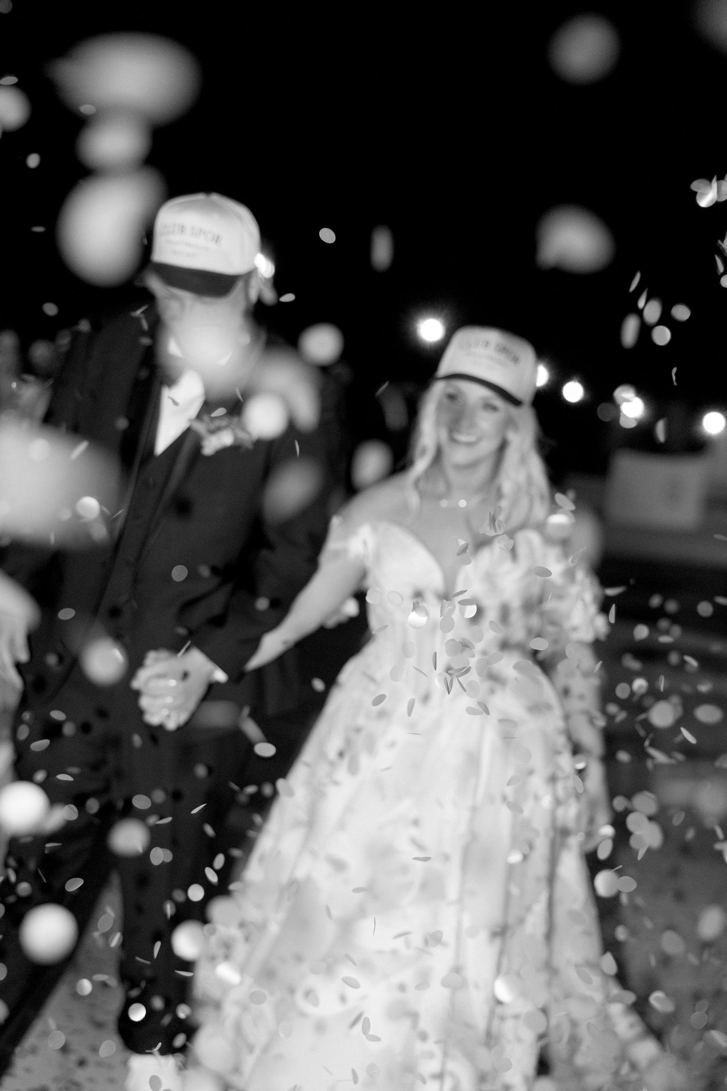 Black and white photo of a wedding celebration with falling confetti creating a magical atmosphere.