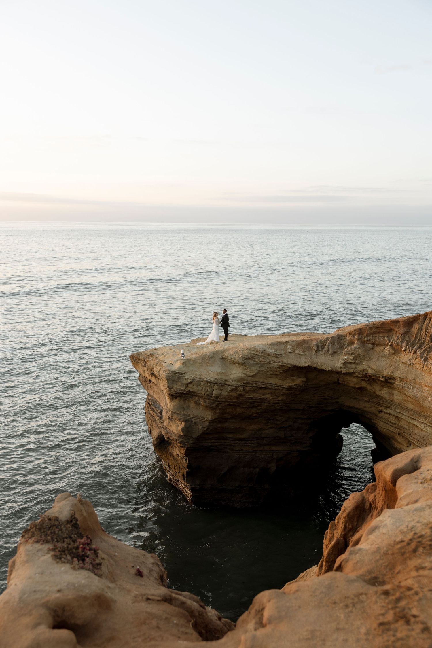 A dramatic coastal cliff formation overlooks the vast ocean during sunset.