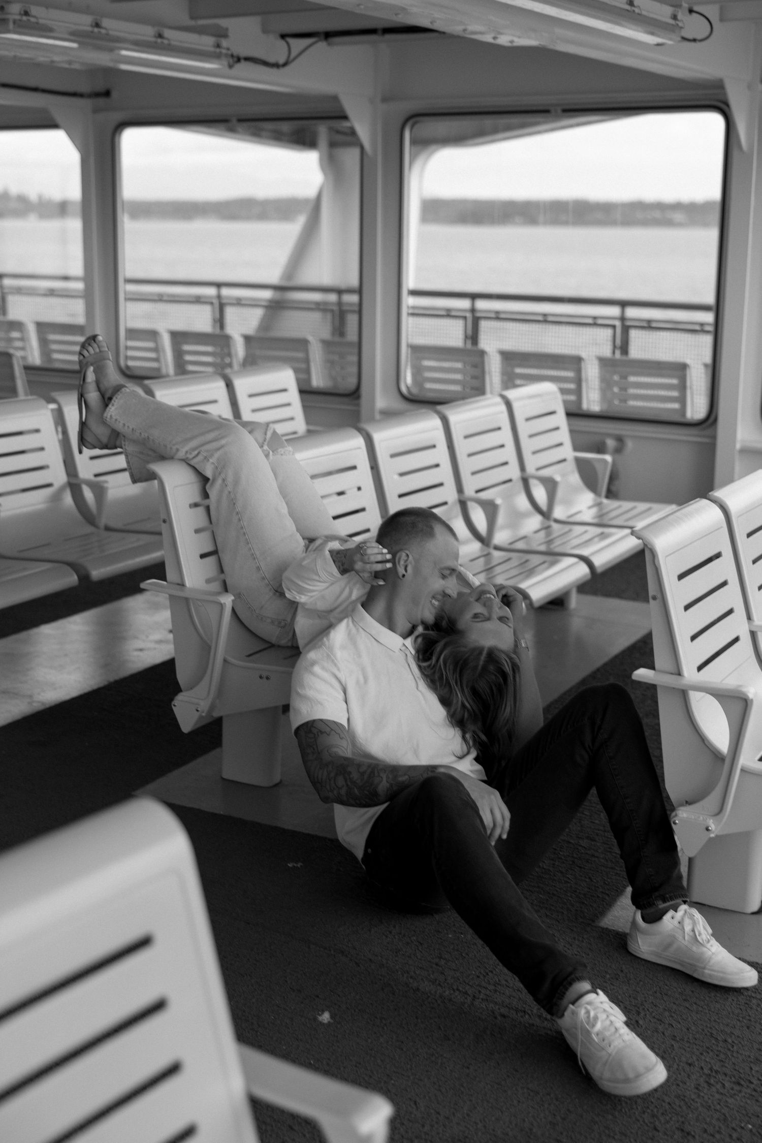 Black and white photo of couple relaxing on ferry seating.