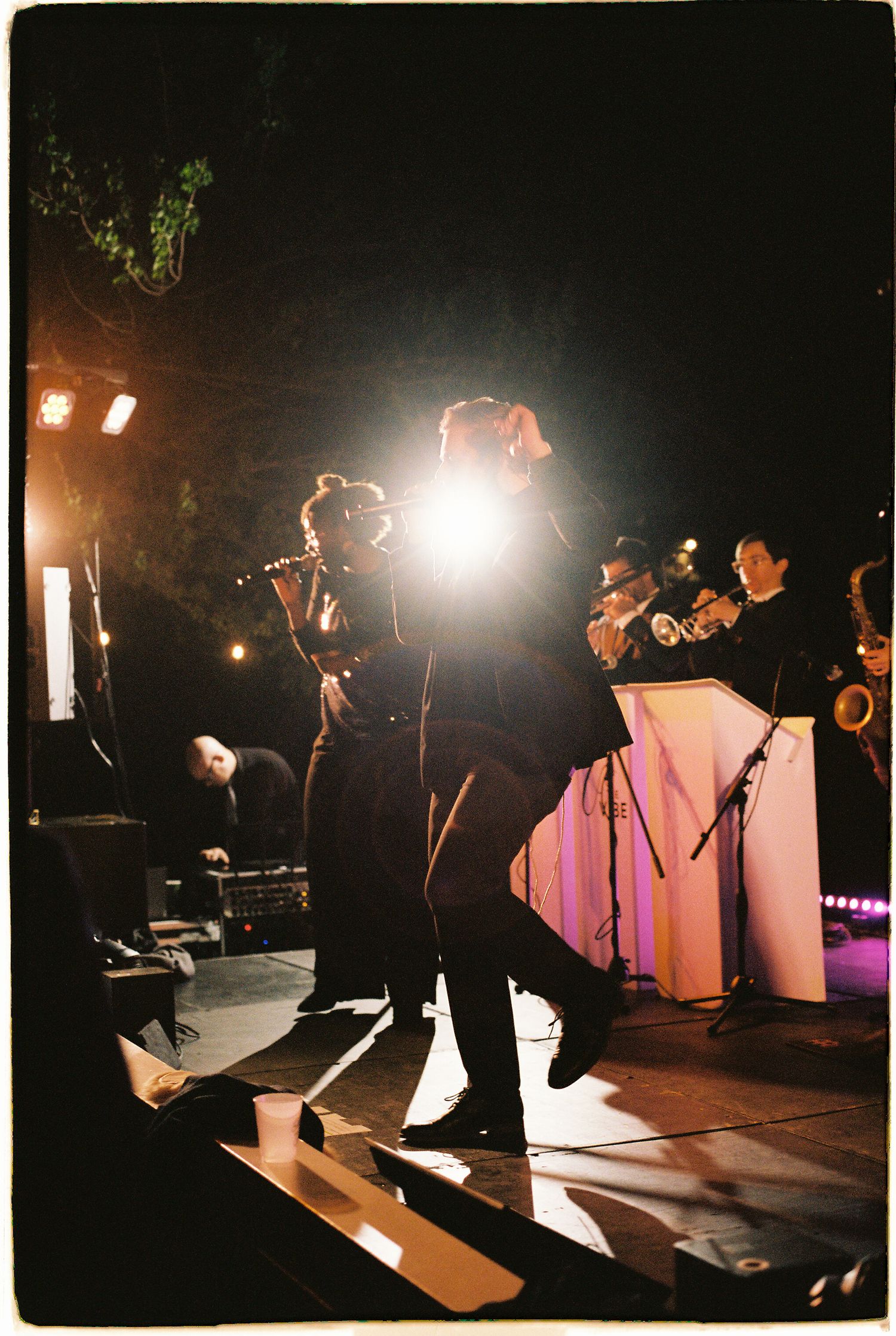 Live wedding band performing on stage with dramatic spotlight during evening outdoor reception.