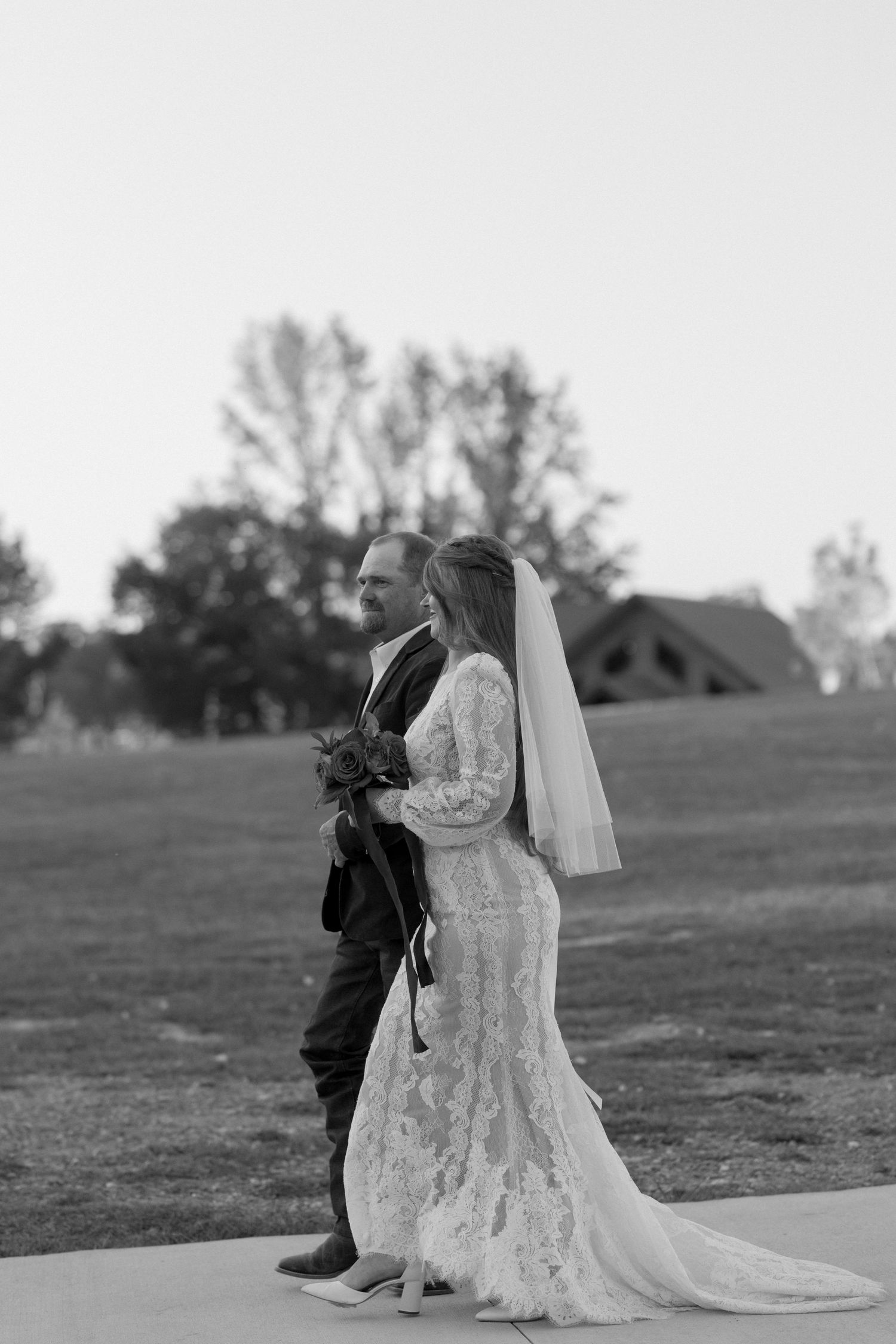 Side profile of couple in formal wear standing together at dusk.