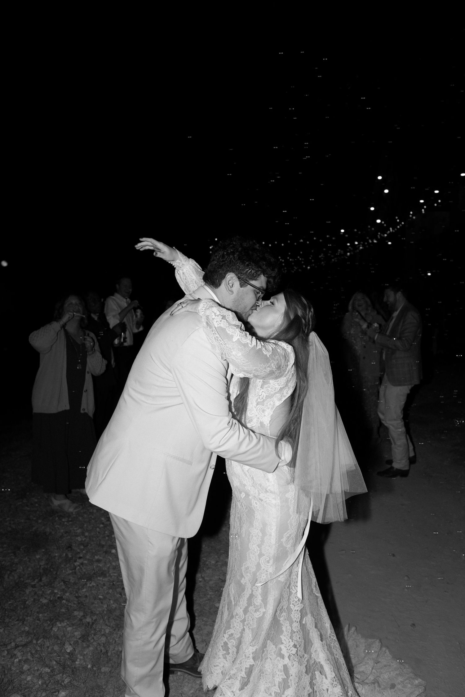 Couple in wedding attire sharing a romantic dance moment at their outdoor nighttime reception.