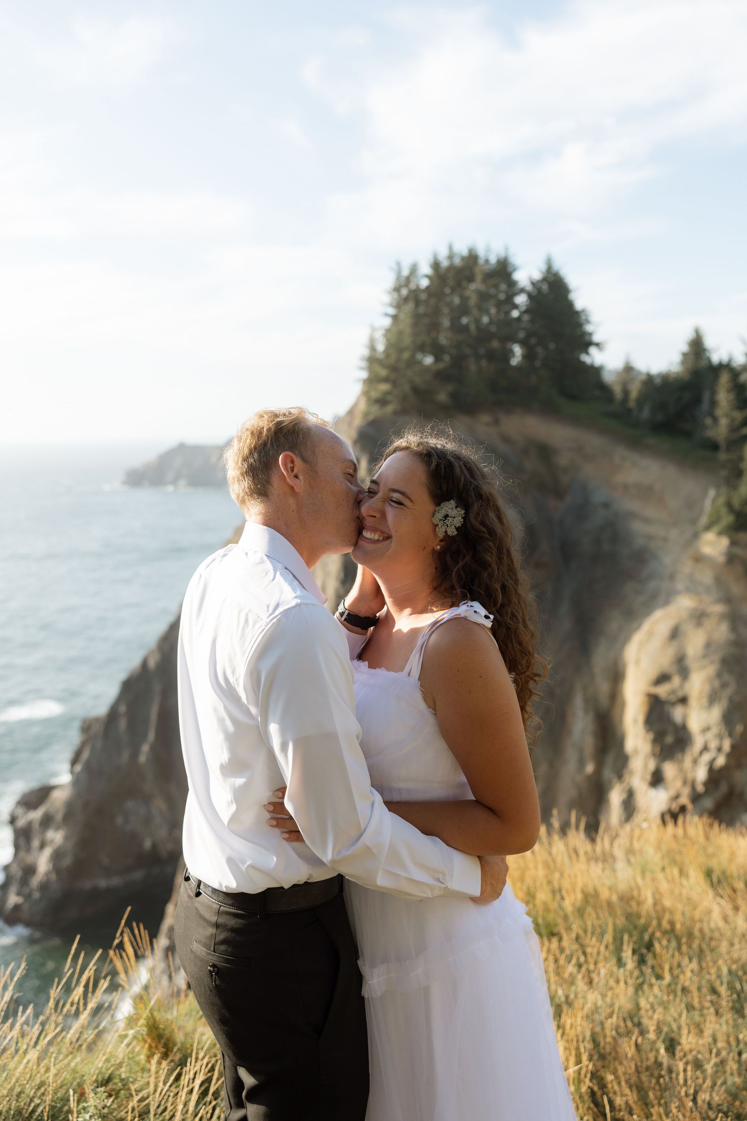 A joyful wedding moment shared between a couple on a scenic ocean cliff.