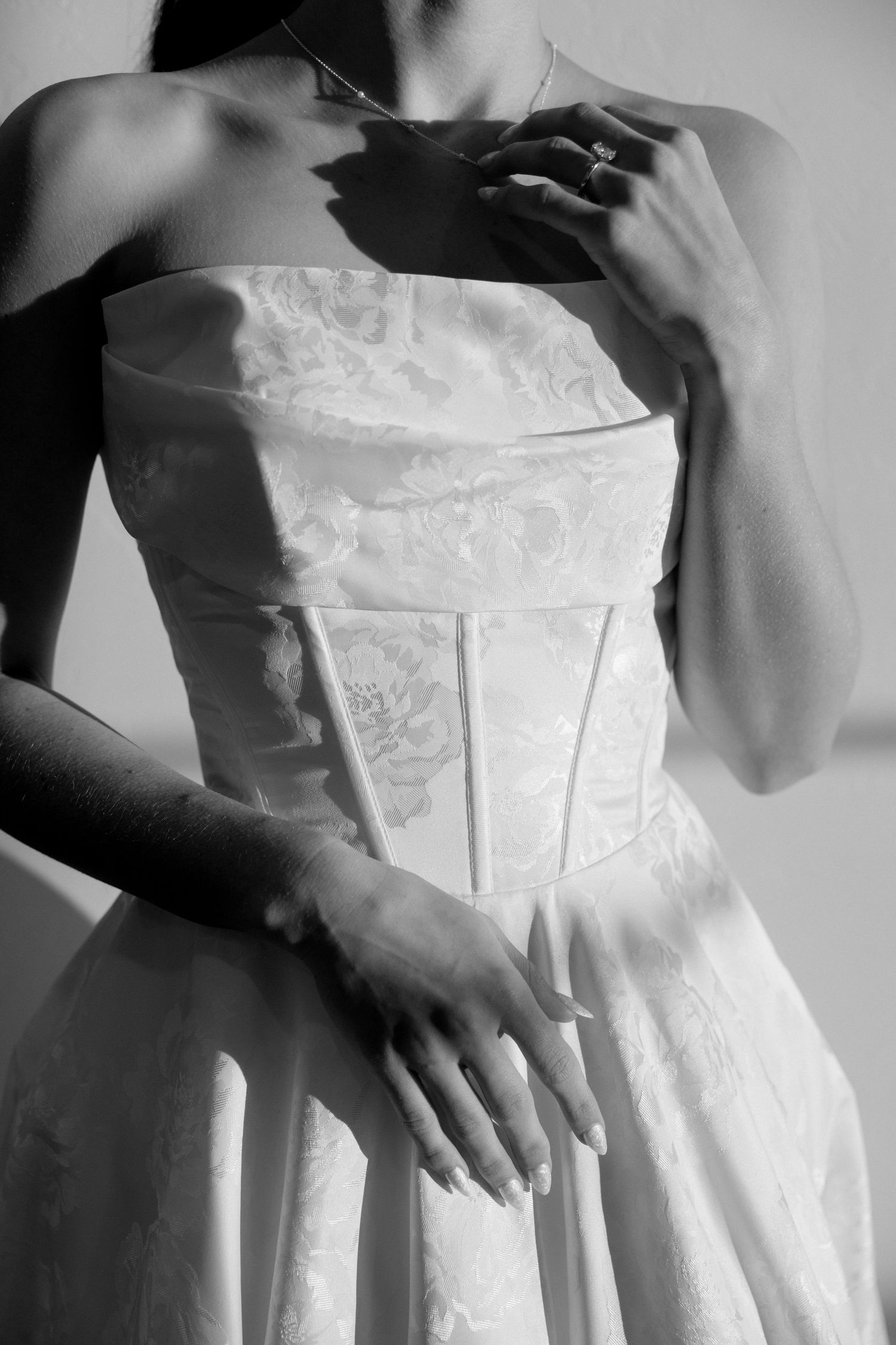 Black and white close-up of a structured strapless wedding dress bodice with lace details.