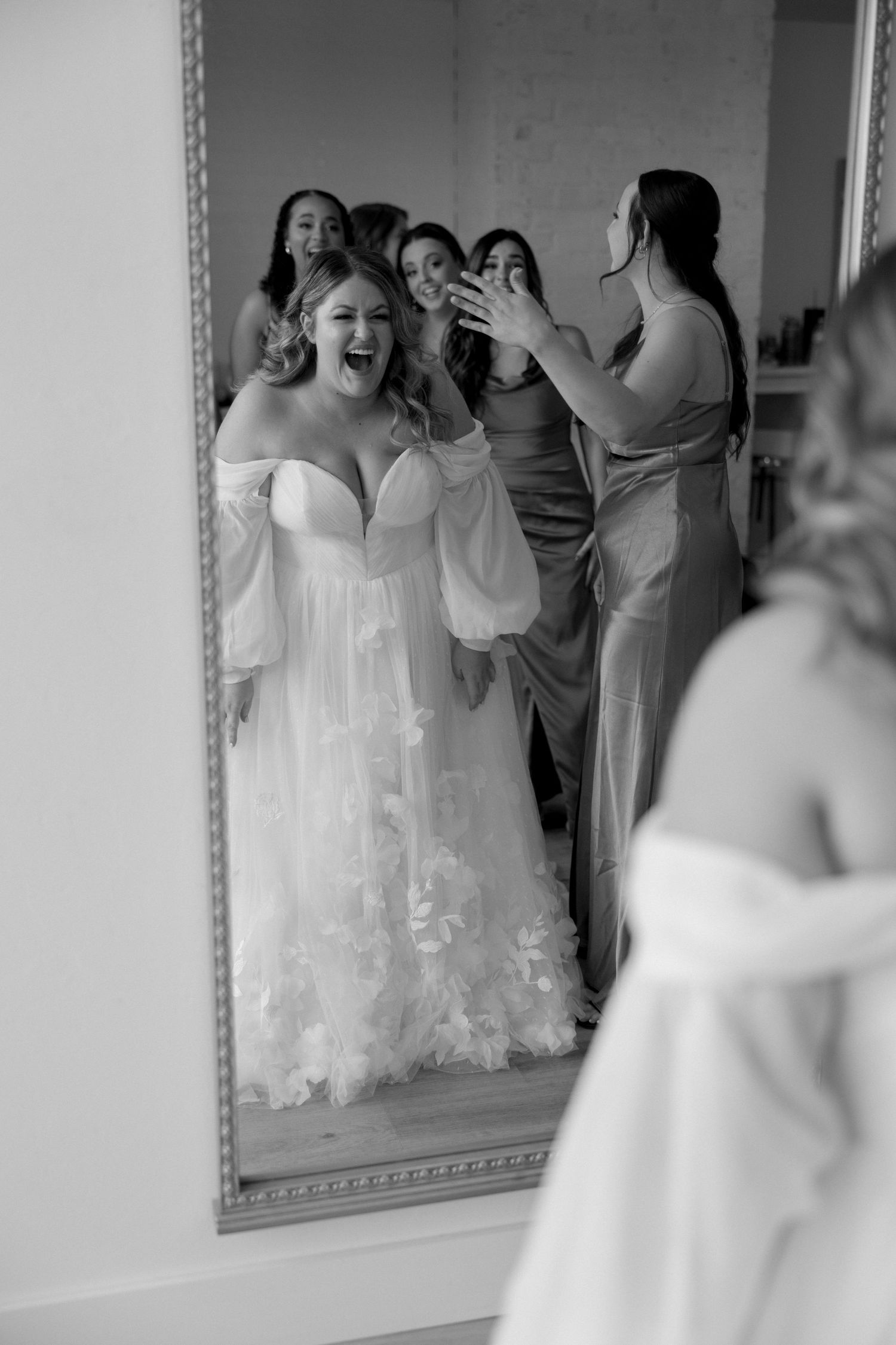 A joyful wedding preparation moment captured in a mirror reflection.