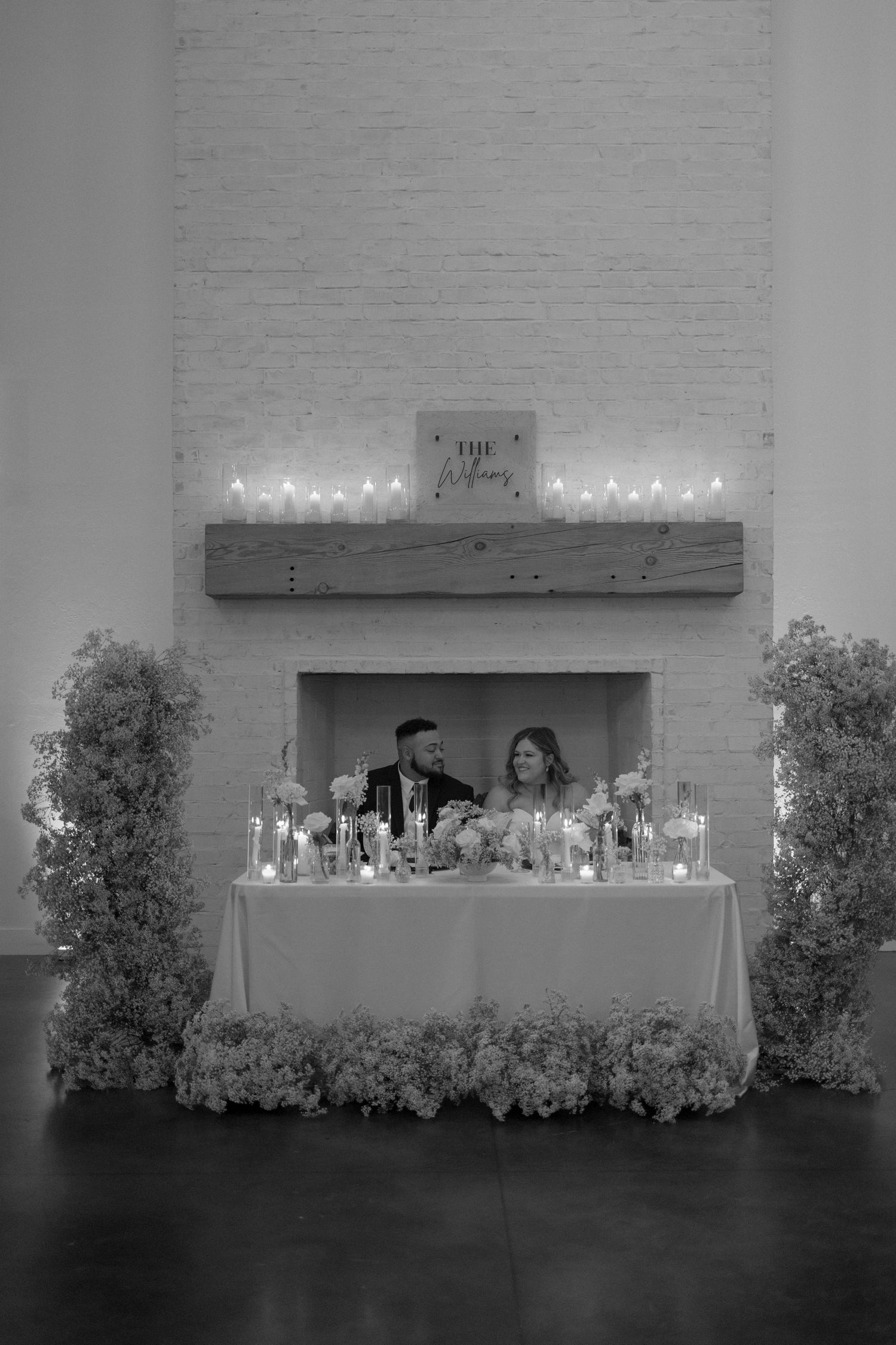 A black and white photo of newlyweds at their elegant sweetheart table.