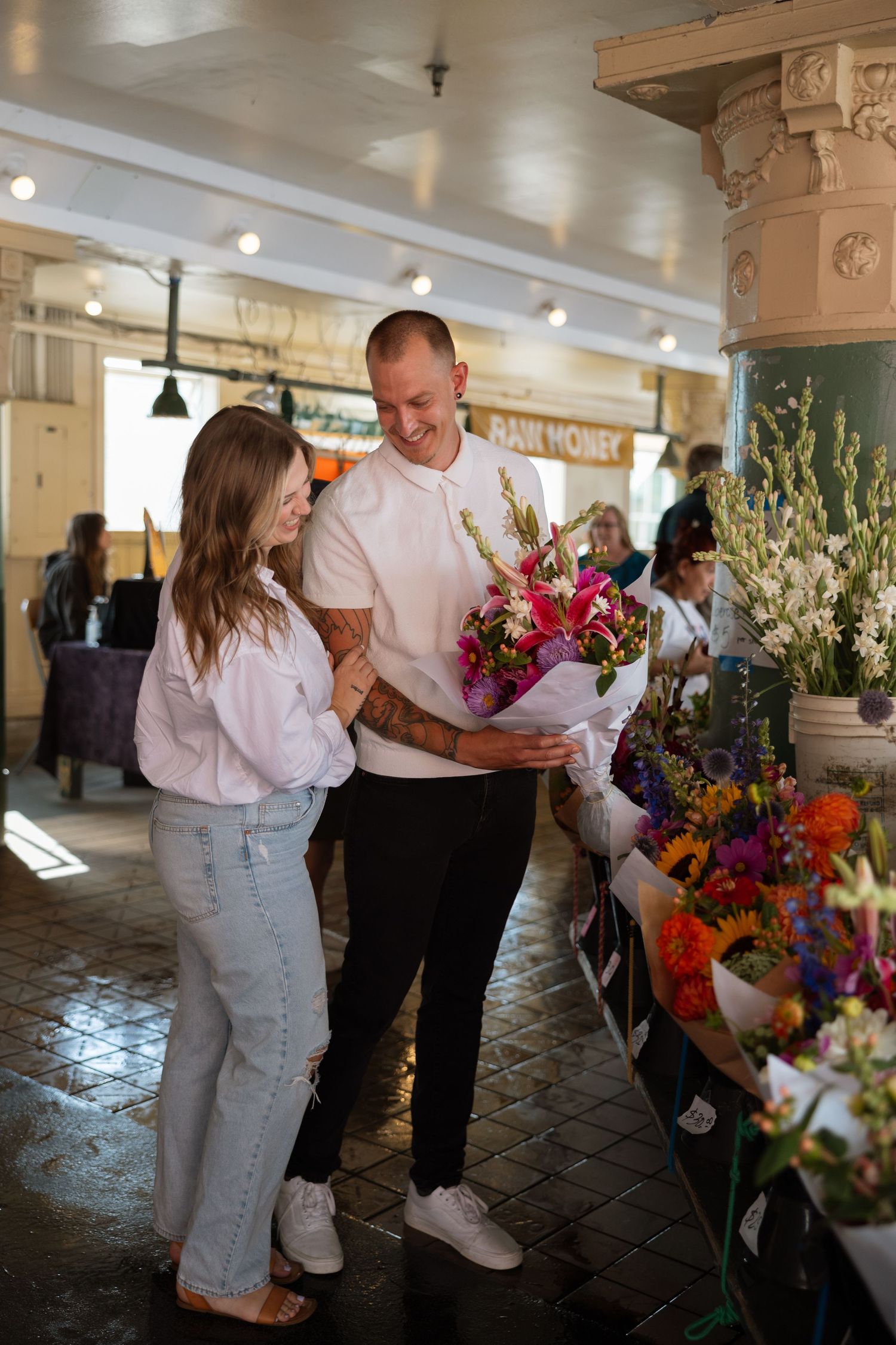 A couple browses colorful flower bouquets at a market stall.