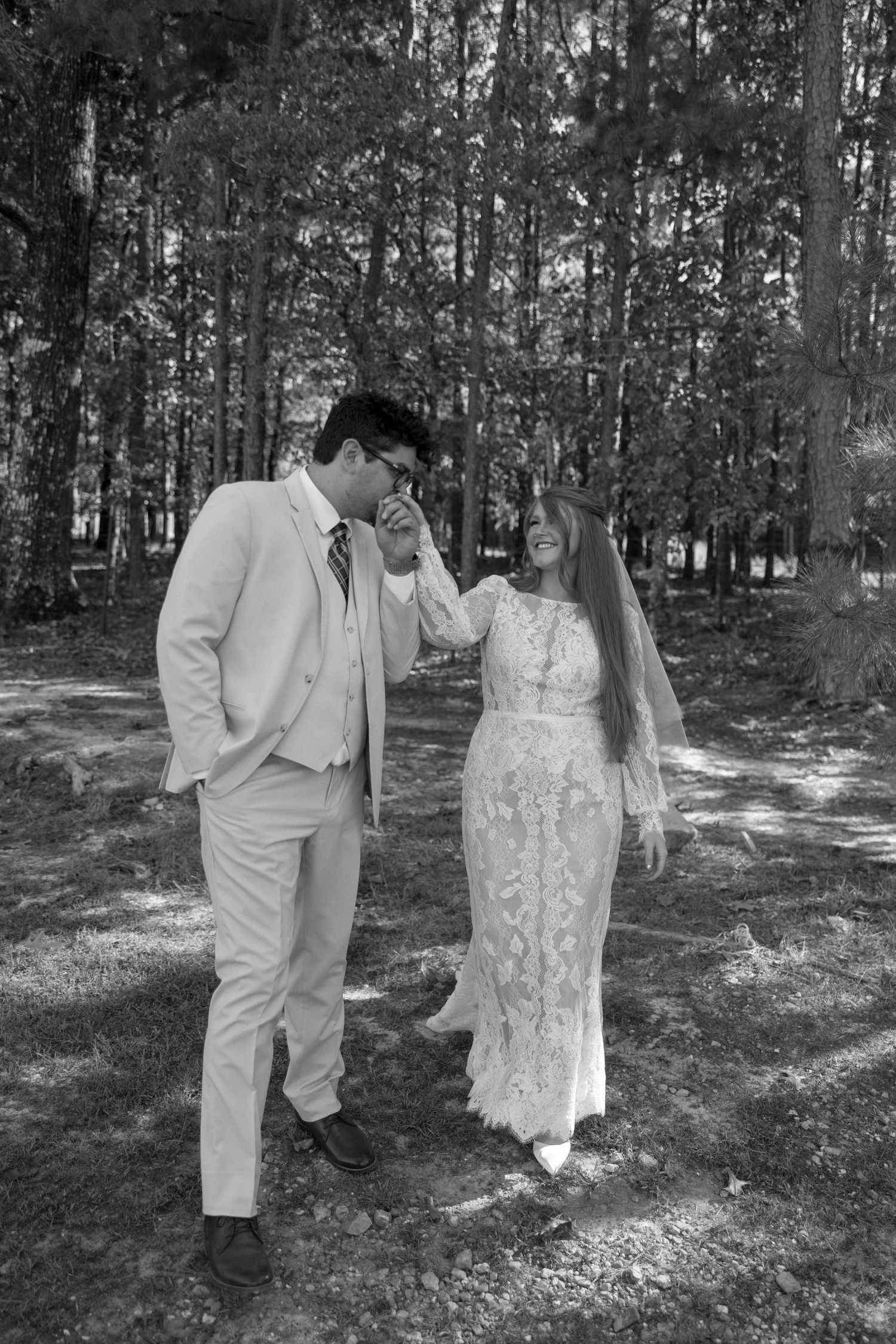 Black and white photo of a couple sharing an intimate moment in a wooded setting.