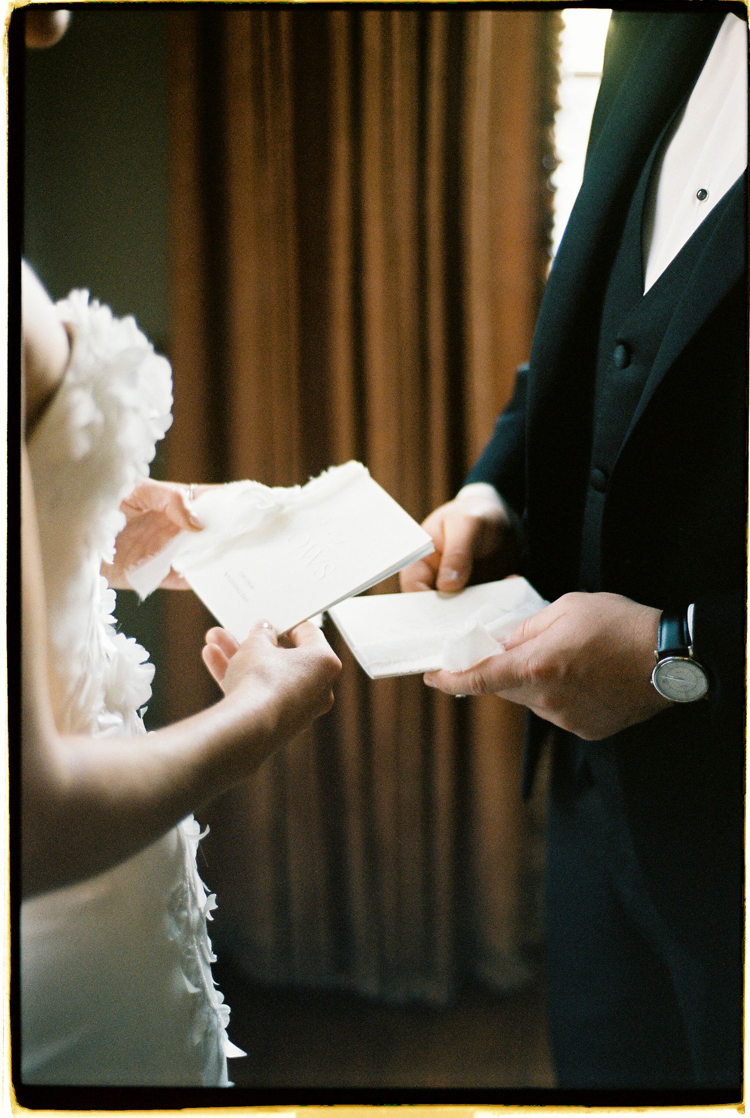 Bride and groom exchanging handwritten vows letters before wedding ceremony.