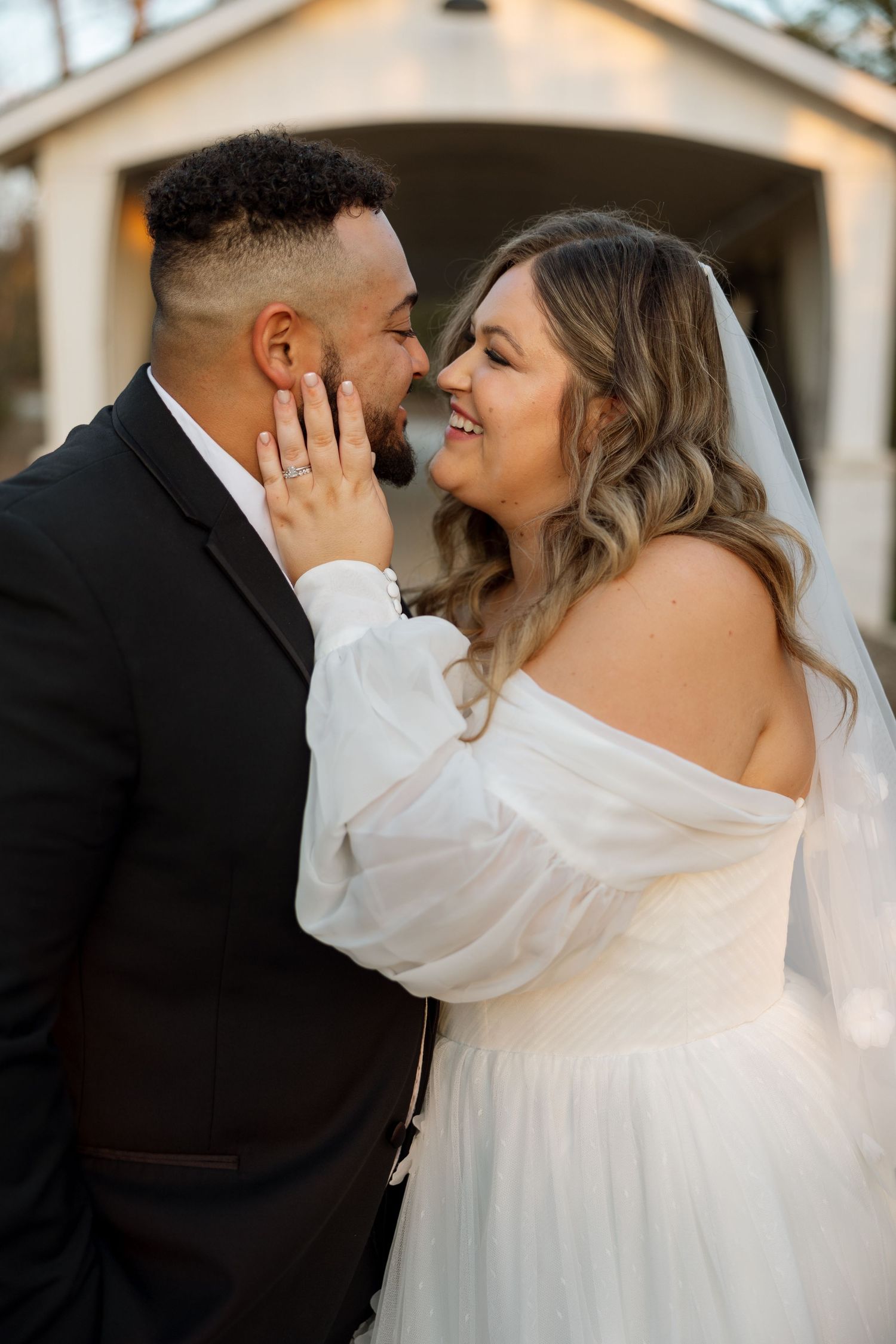 A romantic wedding portrait of a couple sharing an intimate moment outside a chapel.
