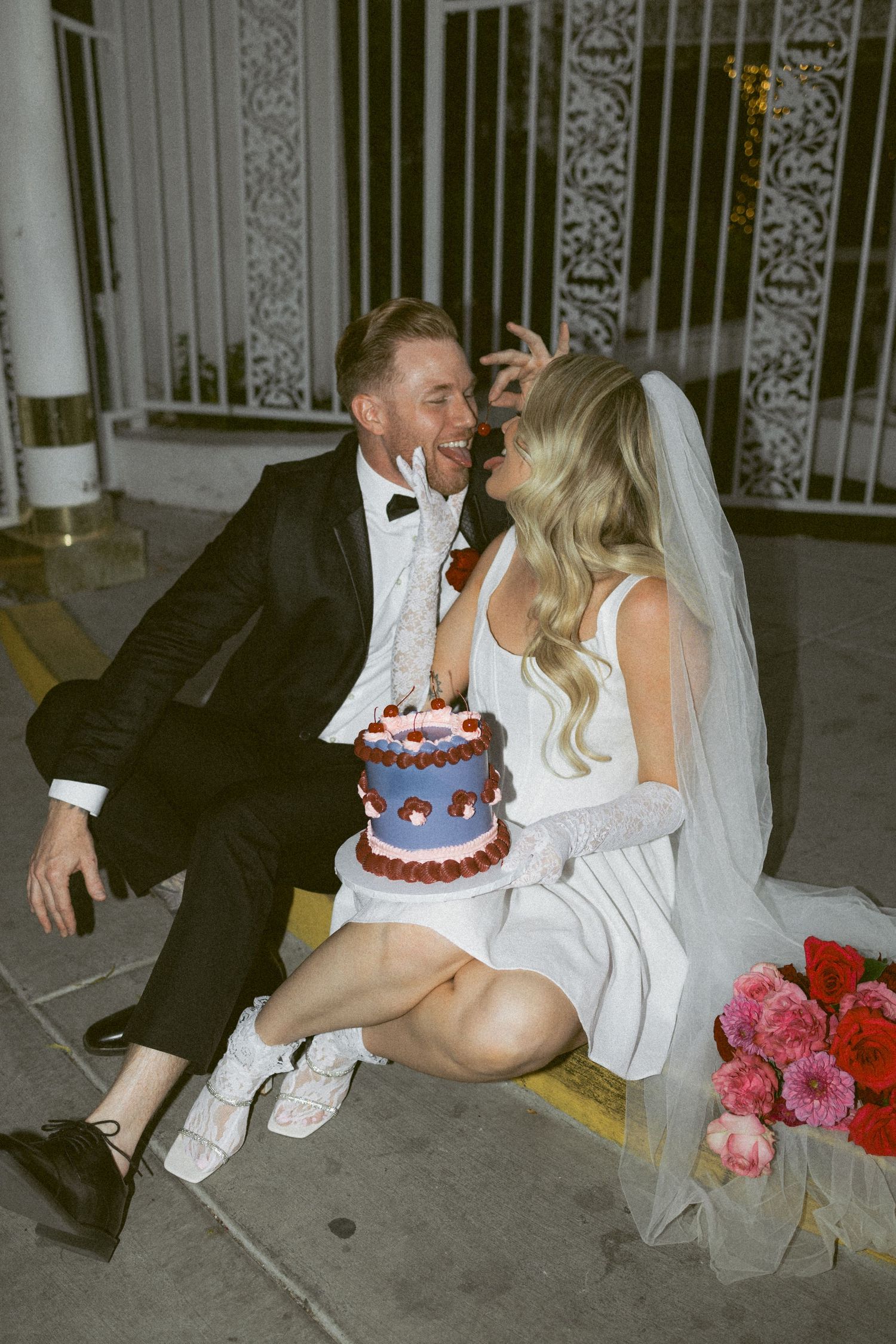 A candid wedding moment outside with small cake and flowers on the ground.