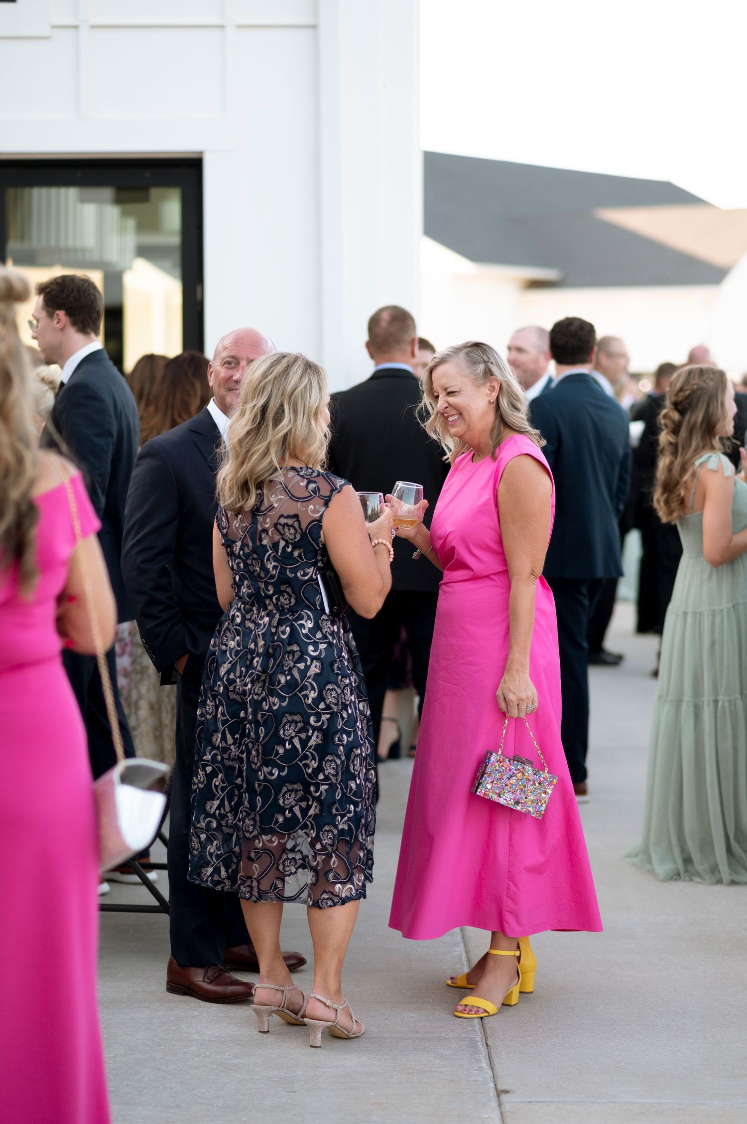 Wedding guests in colorful formal attire mingling during reception.
