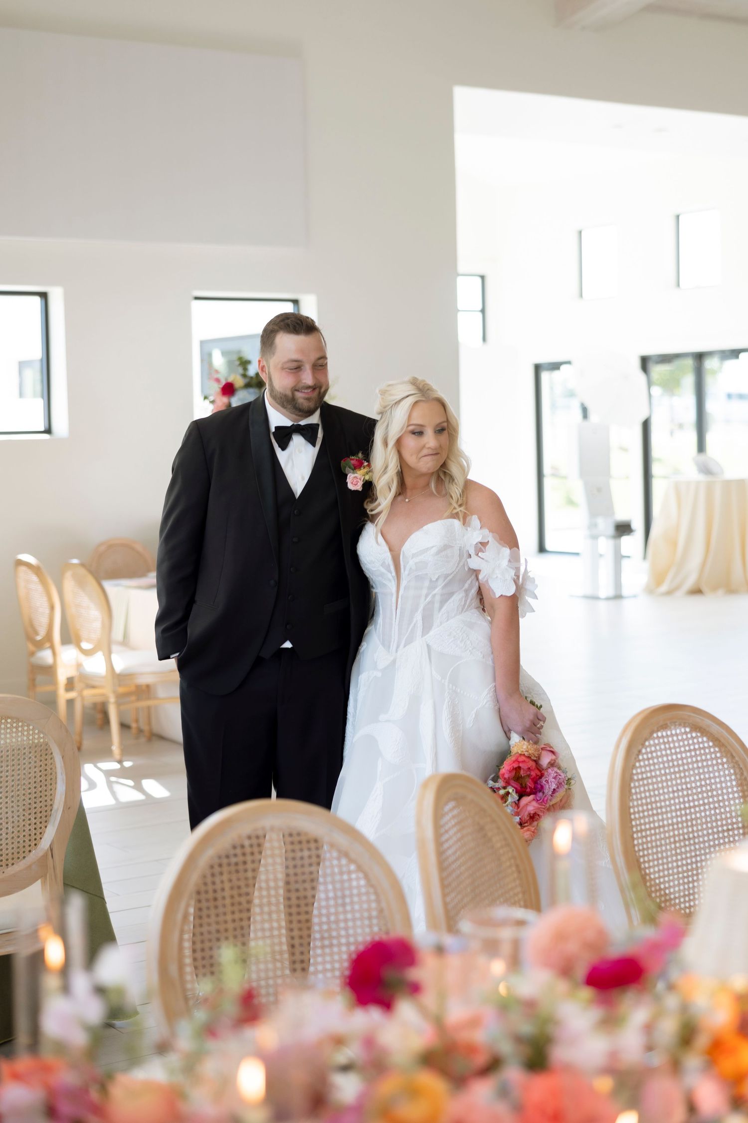 Romantic wedding reception setup with cane chairs and colorful floral centerpieces.