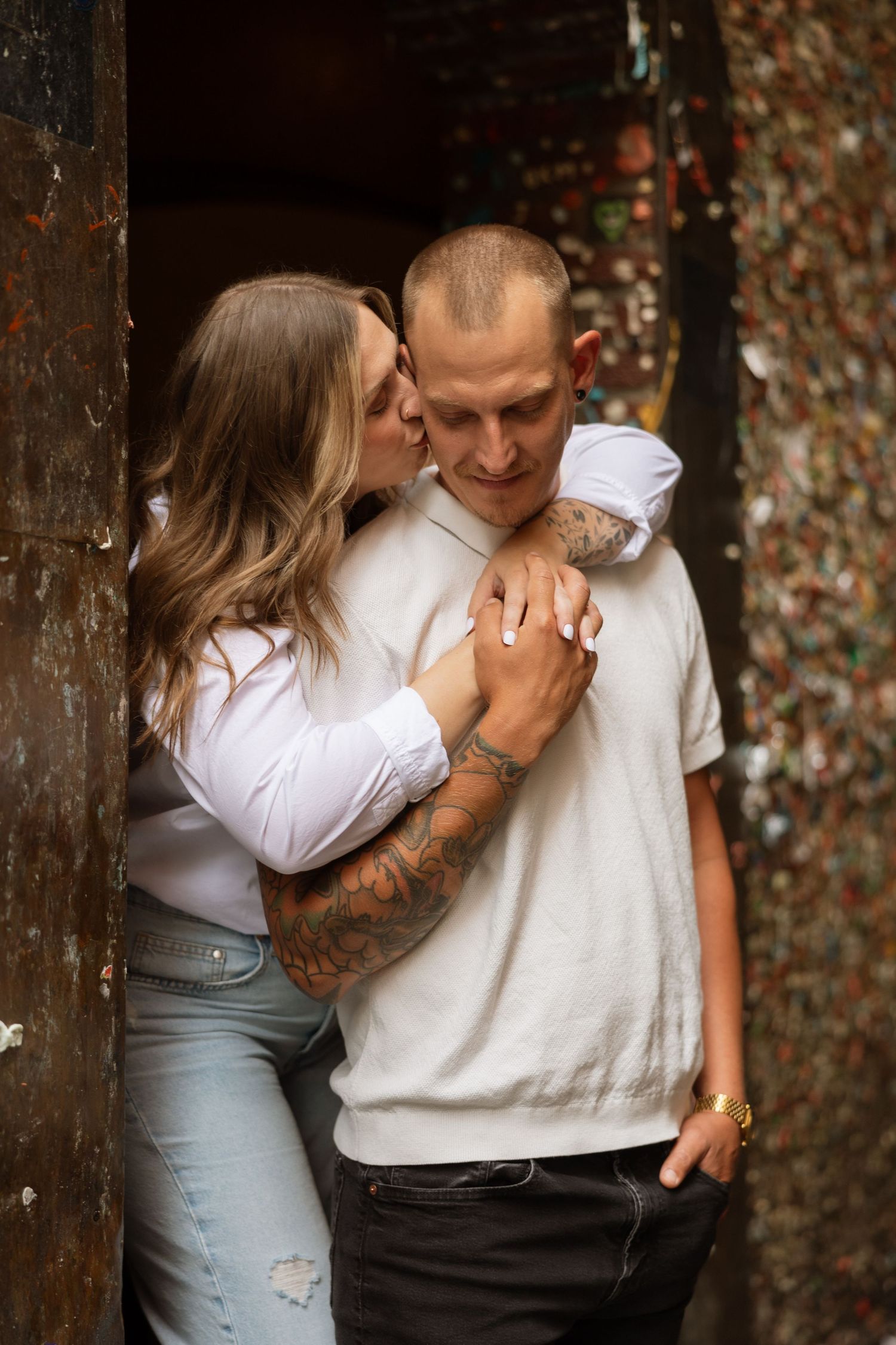 A romantic moment shared between a couple in front of a gum wall in Seattle.