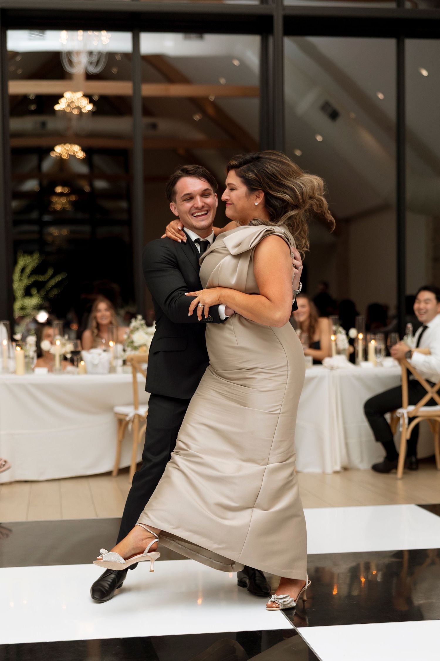 Wedding couple shares a joyful dance moment during their reception in an elegant indoor venue.