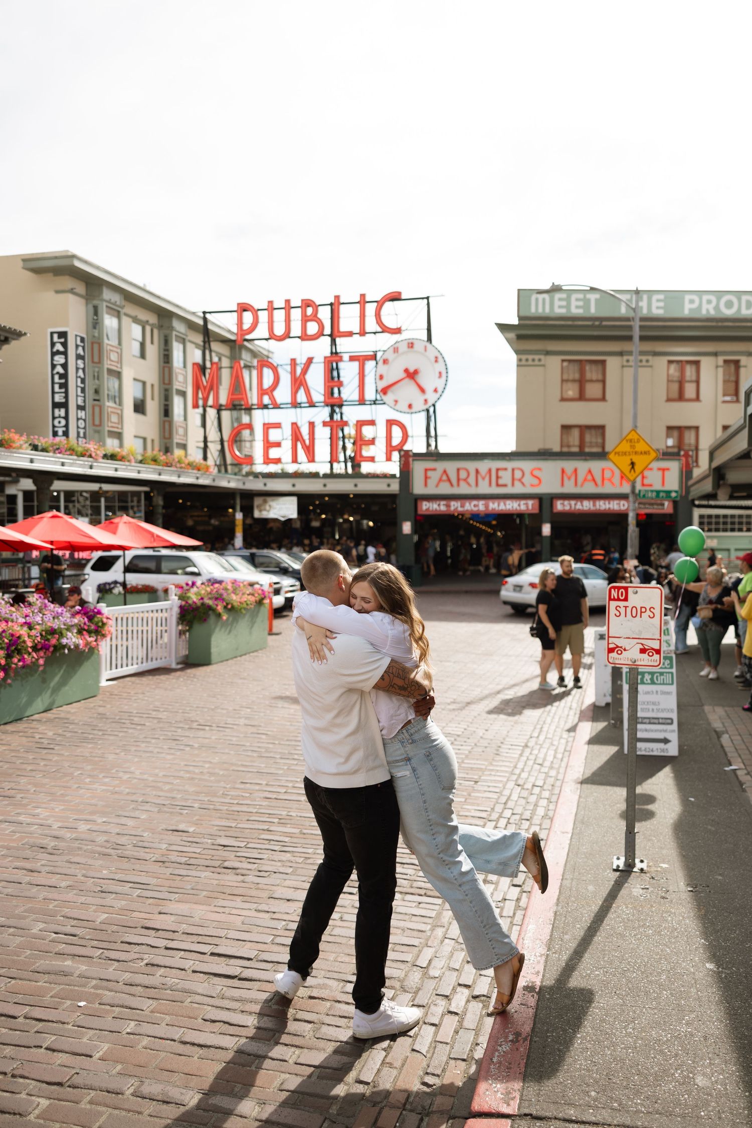 A couple dances and celebrates under the Pike Place Market sign in Seattle.