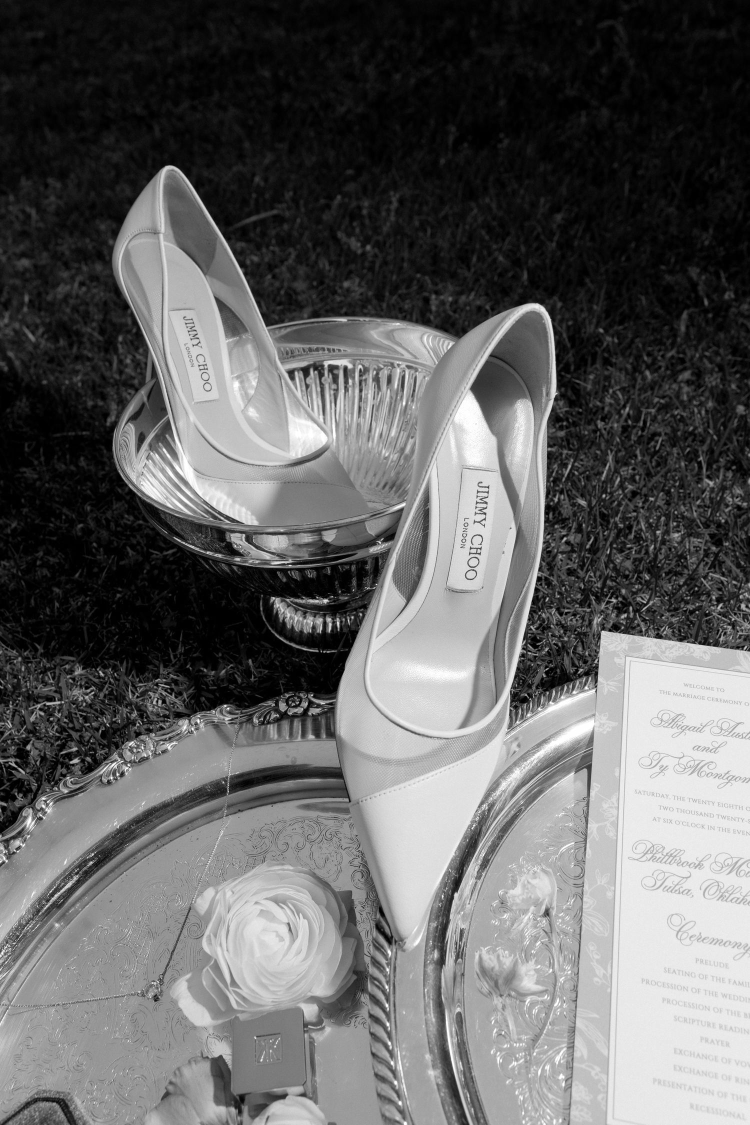 Jimmy Choo bridal heels displayed on silver tray beside wedding invitation and white rose in black and white.