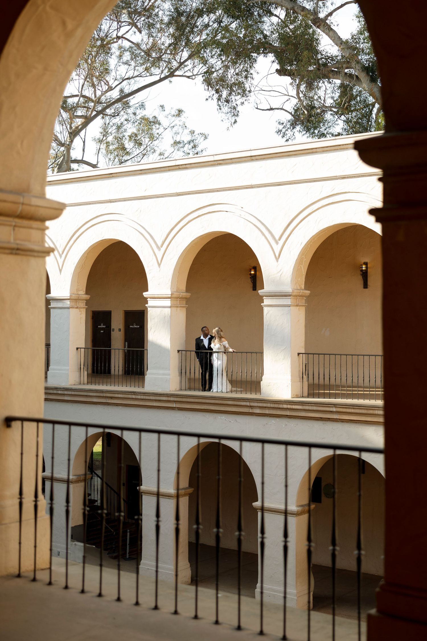 An outdoor wedding venue with cream-colored arched colonnade and wrought iron railings.