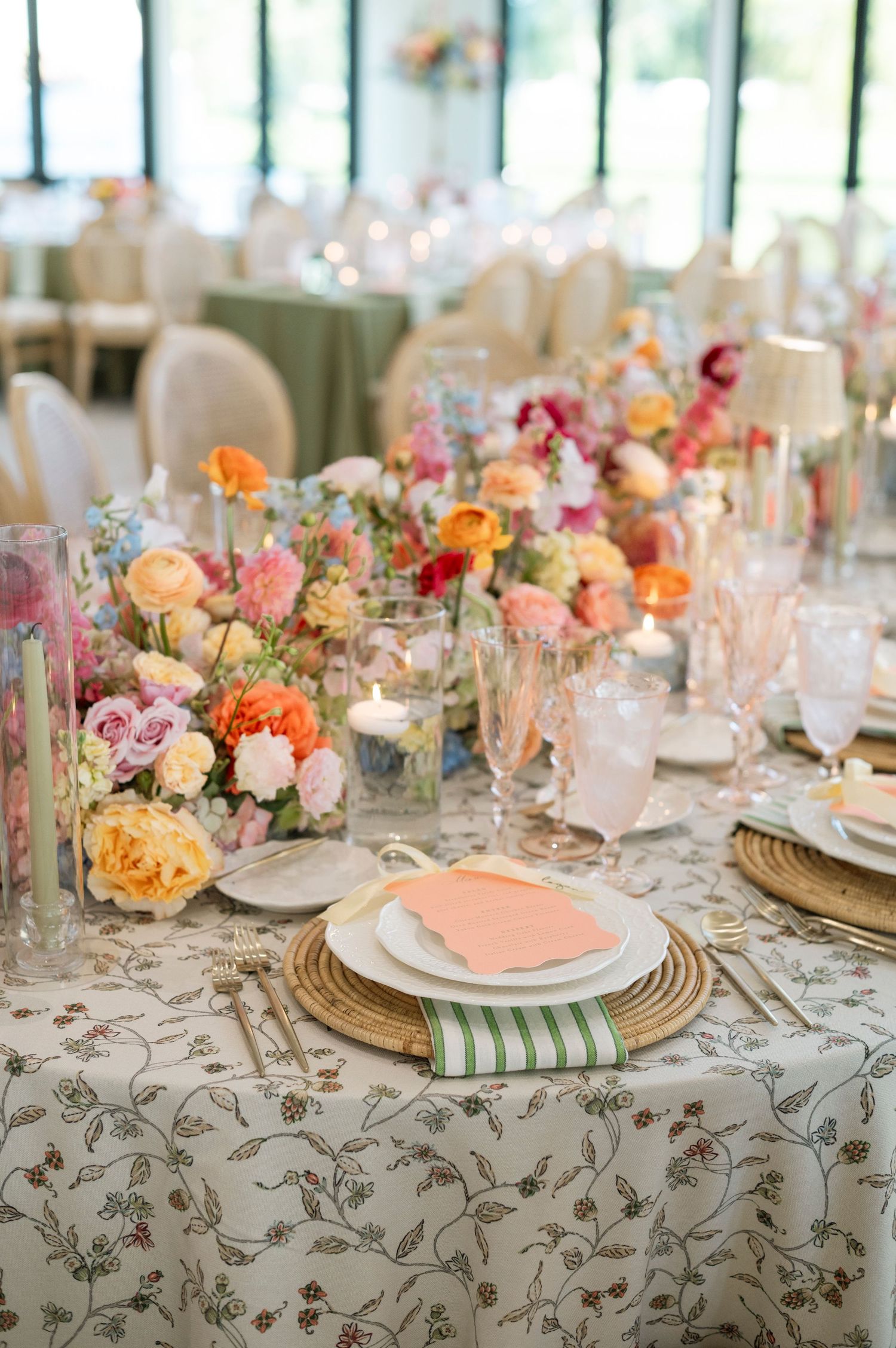Elegant table settings with colorful floral centerpieces and gold charger plates on patterned linens.