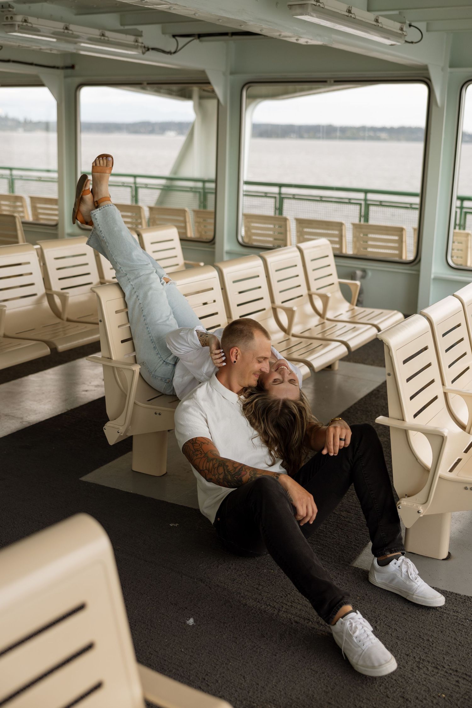 Couple being playful on ferry benches during transit across water.