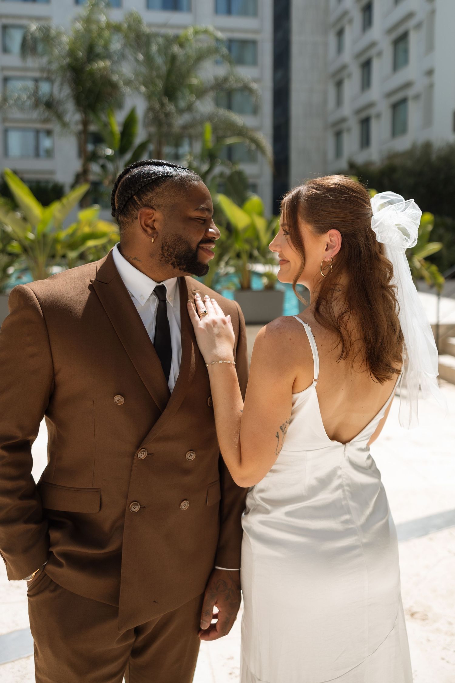 Intimate moment between newlyweds sharing laughter in a tropical garden setting.