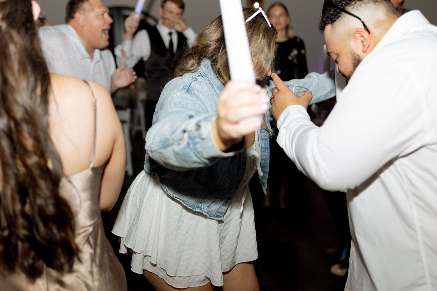 Wedding guests dancing with glow sticks during an energetic reception celebration.