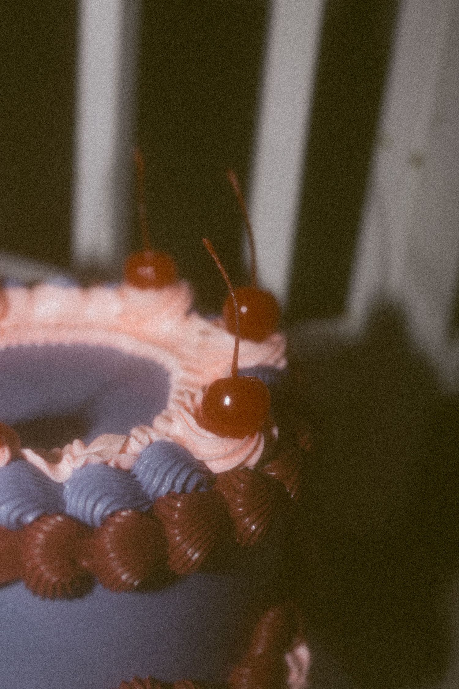 Detailed view of cherries decorating a wedding cake with pink and purple frosting.