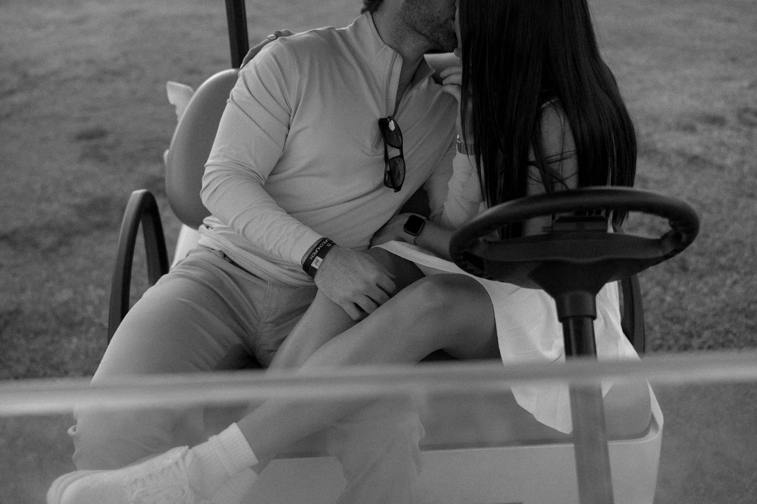 An intimate black and white photo of a couple in white clothing sitting close together.