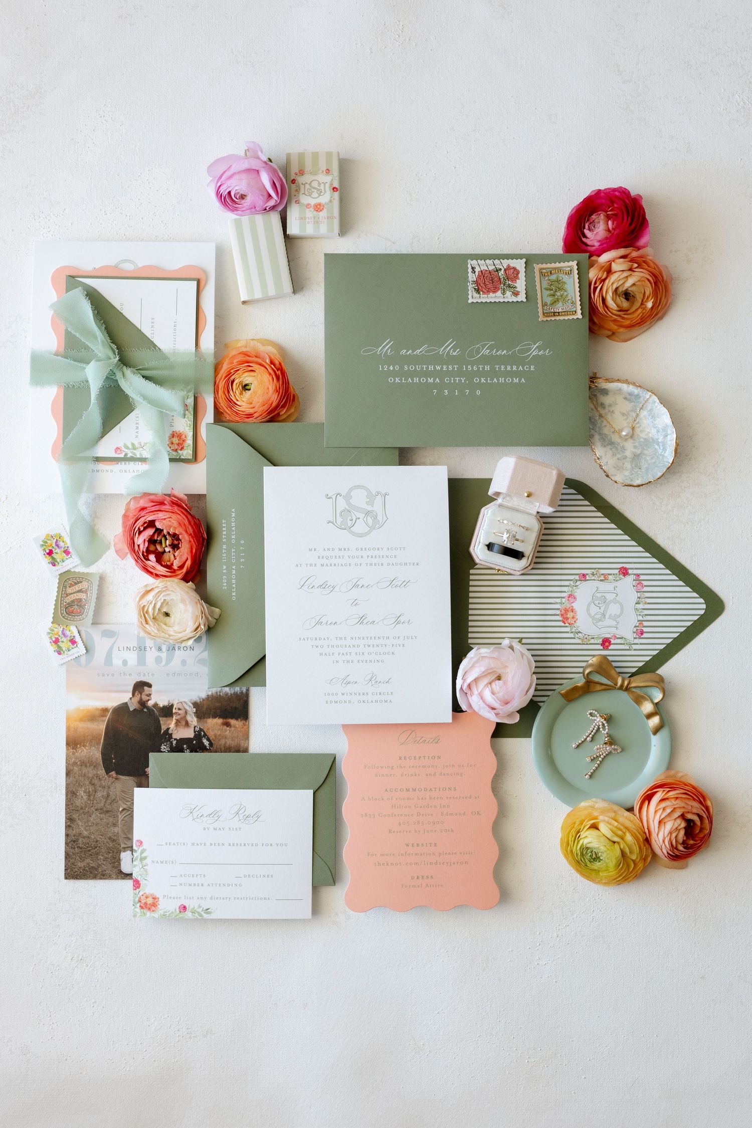 Wedding invitation suite with sage green and coral details arranged with delicate flowers and vintage stamps.
