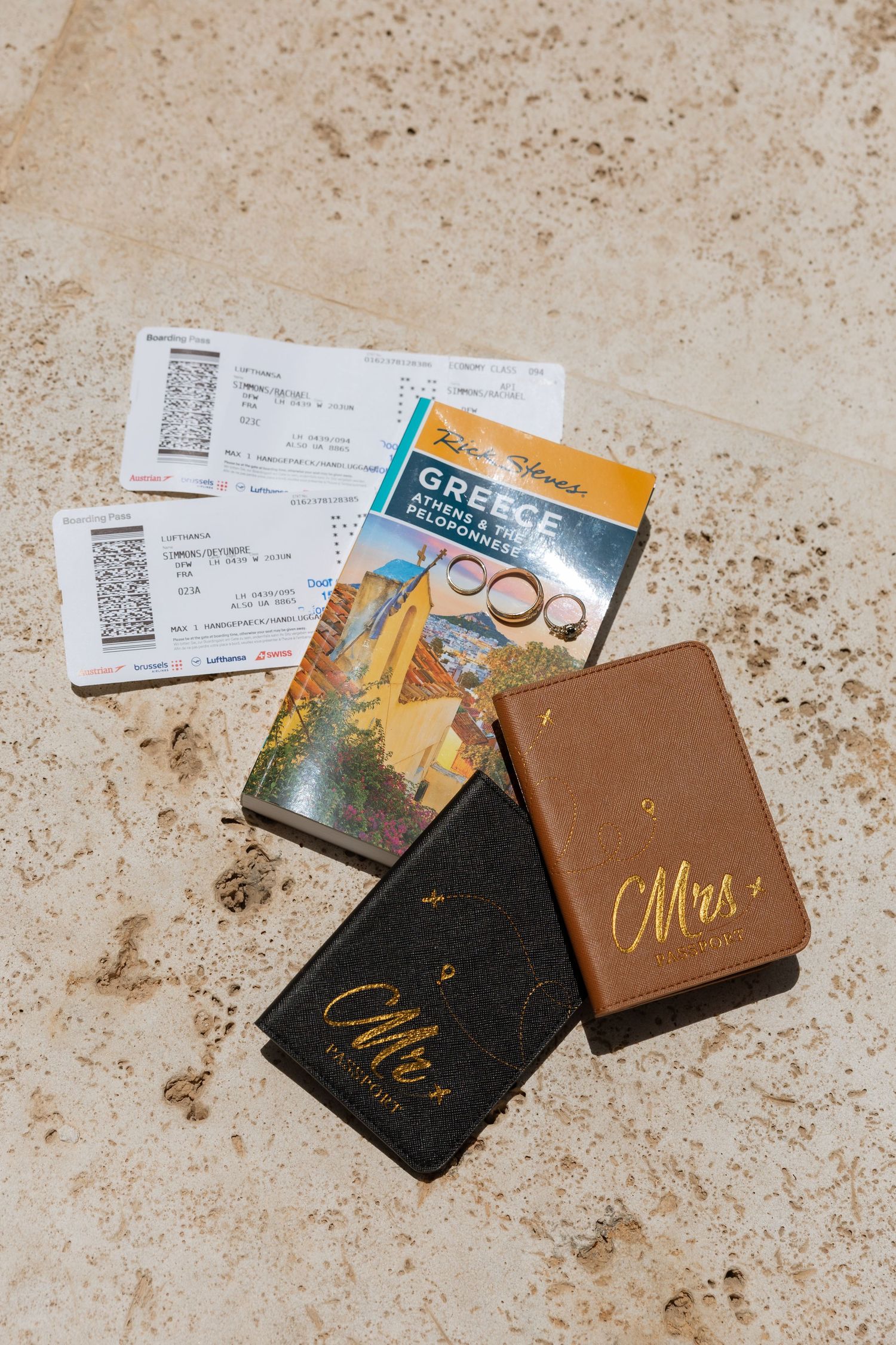 Wedding travel essentials including passports, tickets and guide books laid on stone surface.